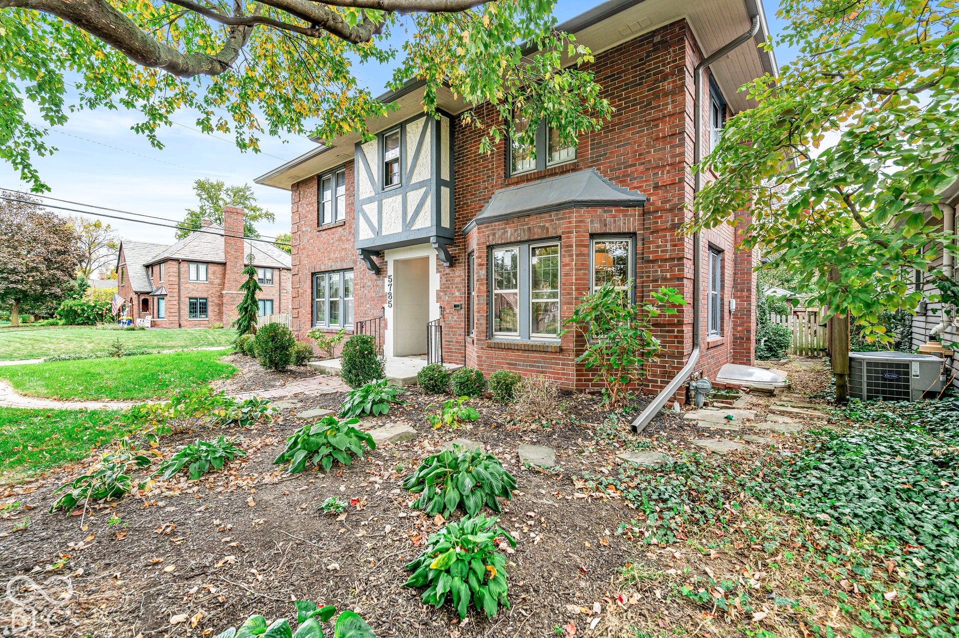 Brick exterior featuring timber-framing details, a bay window, and a recessed entryway with a stone walkway