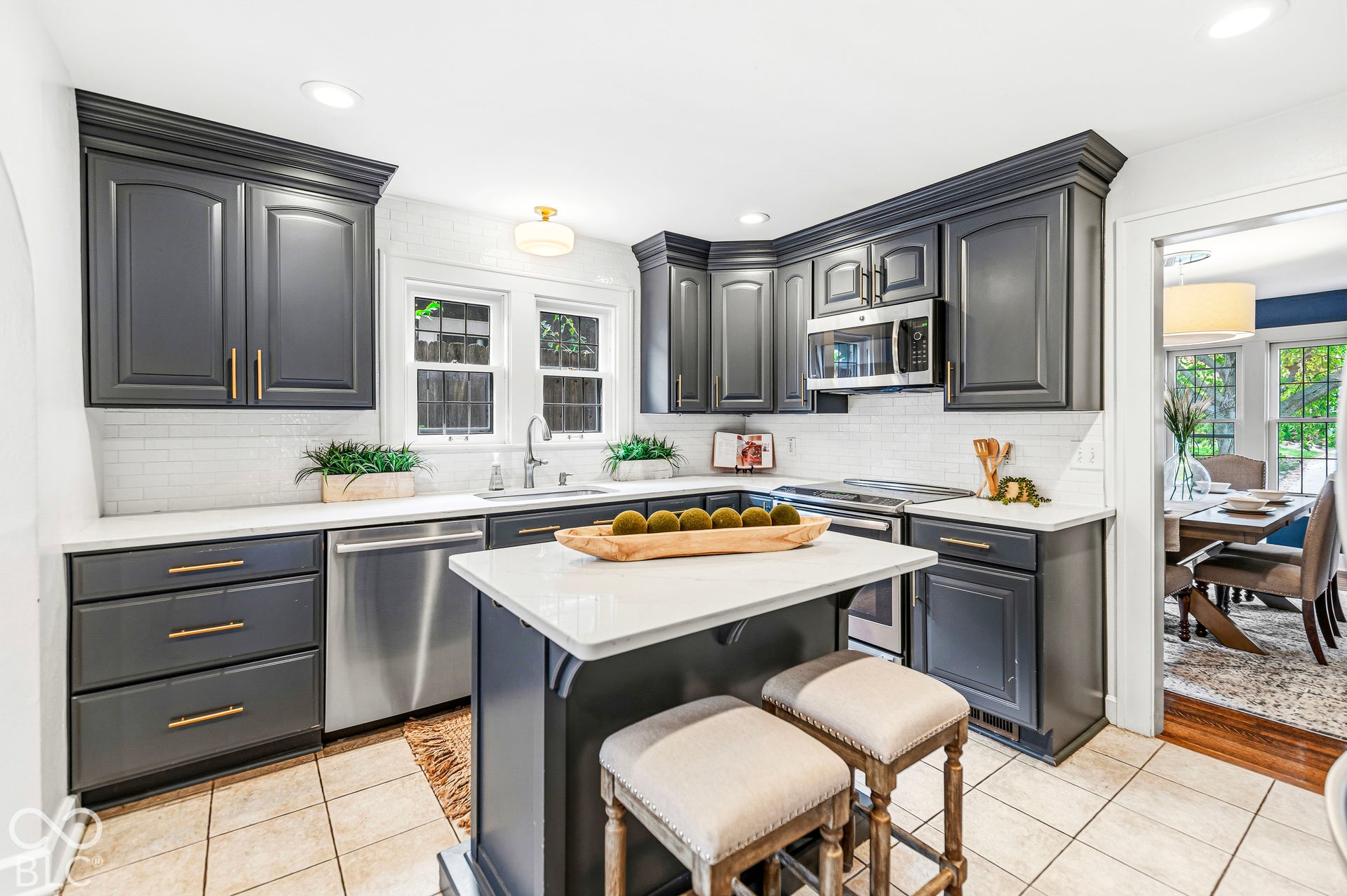 Kitchen featuring dark-toned cabinetry, a central island with quartz surfacing, stainless steel appliances, and subway tile backsplash