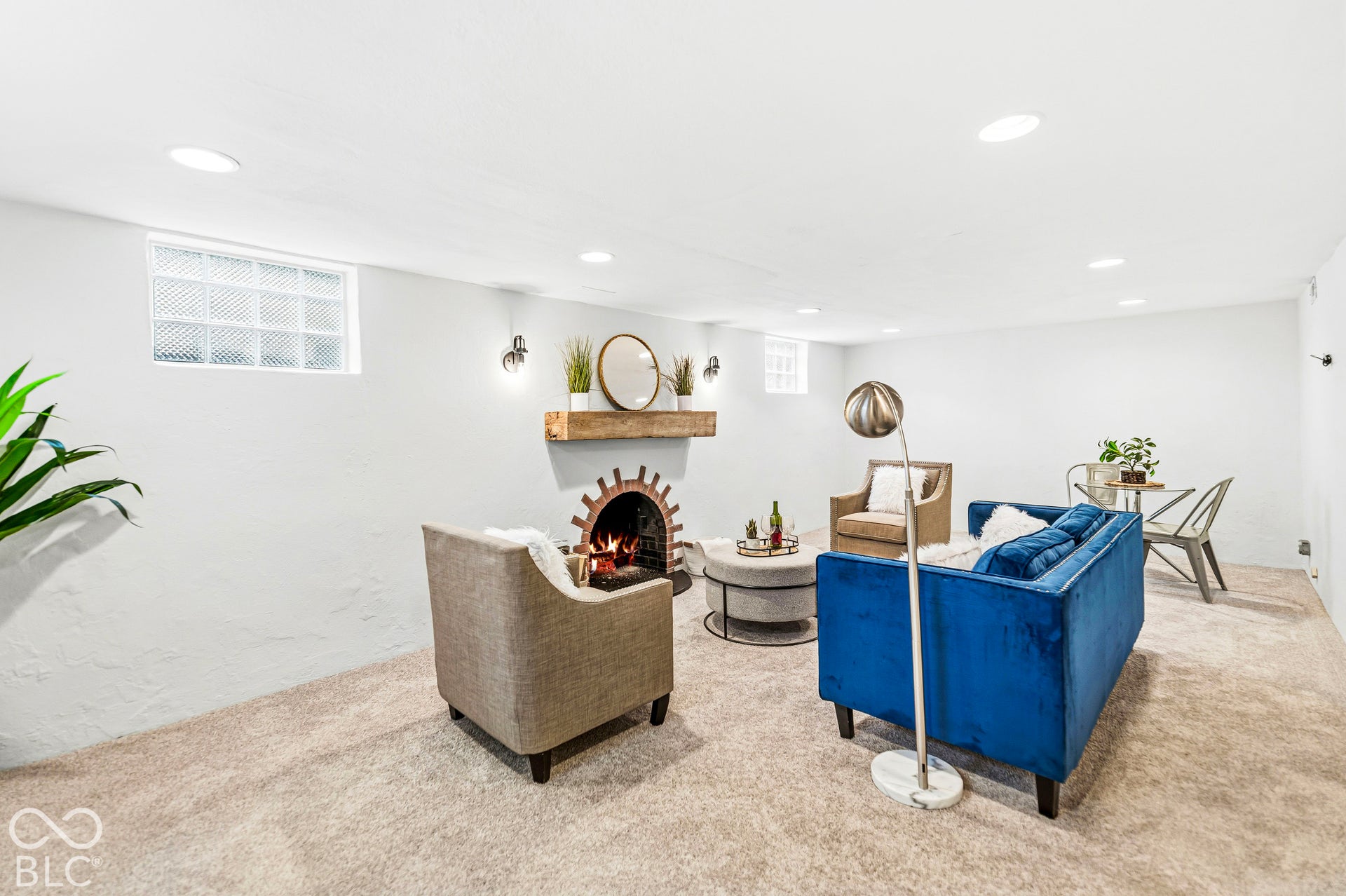 Interior space featuring carpeted flooring, recessed ceiling lighting, glass block windows, and a masonry-style fireplace with a floating wood mantel