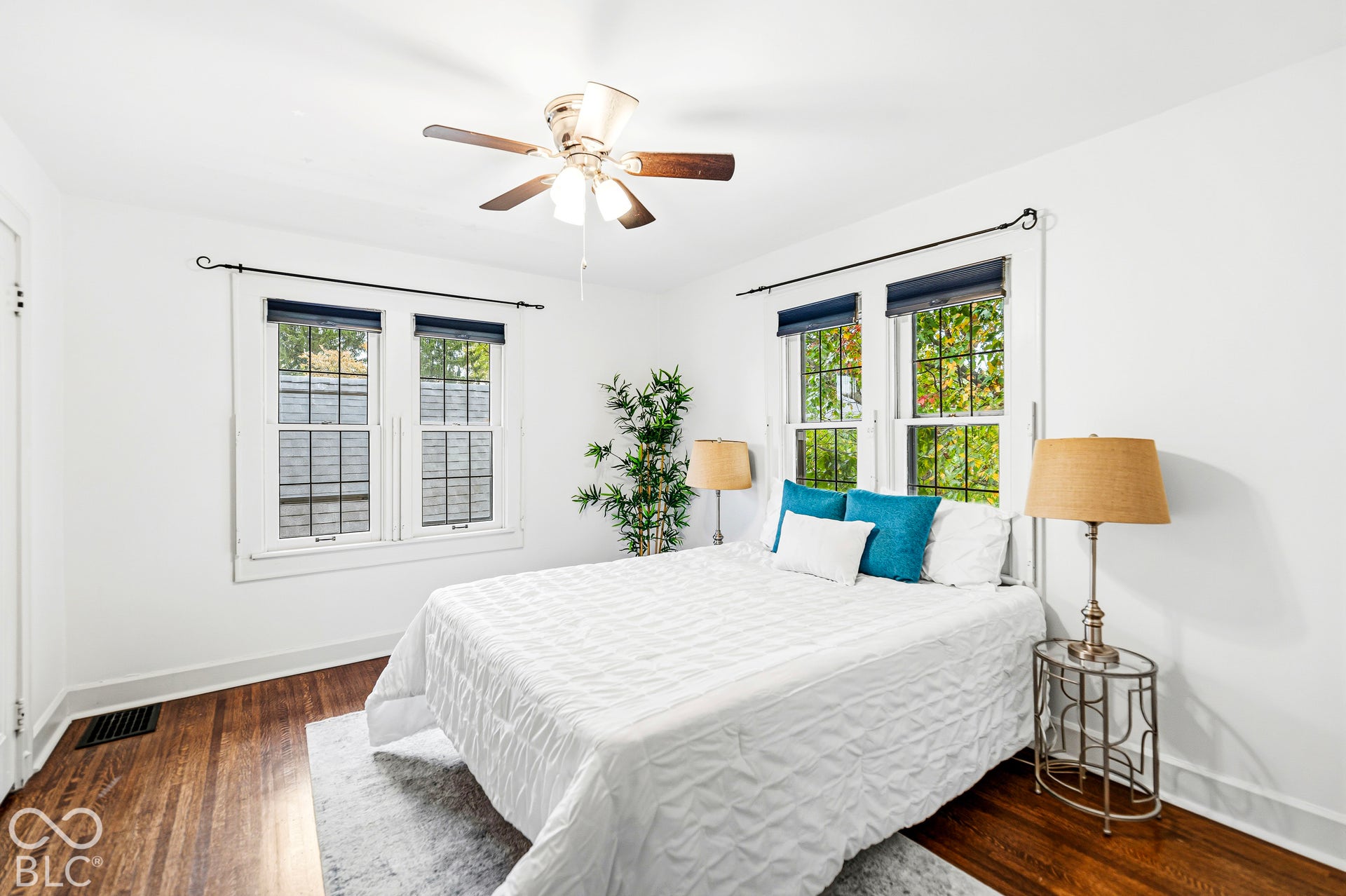 Room featuring dark-stained wood-finish flooring, multi-pane windows, and a central ceiling fan with integrated lighting
