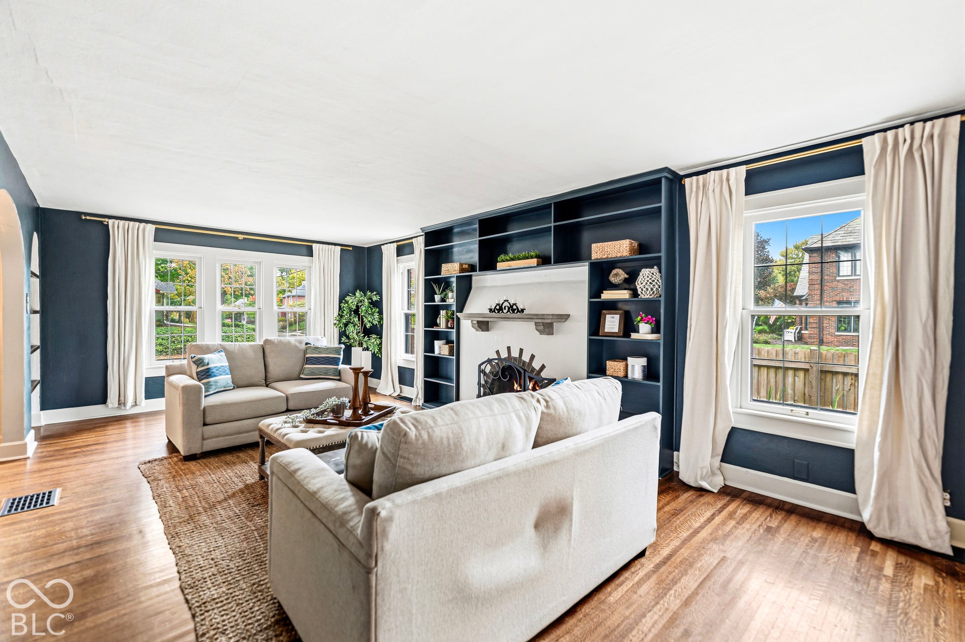 Living area featuring wood-finish flooring, floor-to-ceiling built-in shelving, and a central fireplace with a mantel