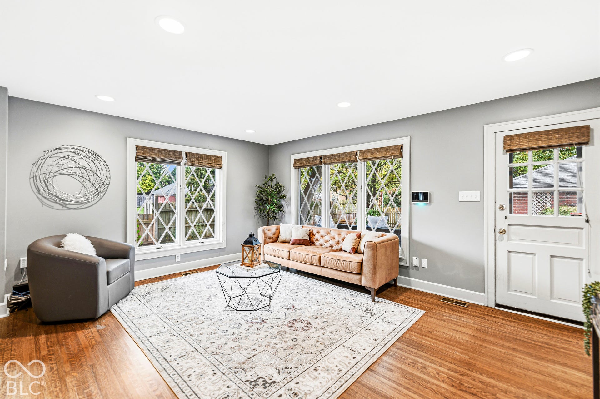 Wood-finish flooring, diamond-grid windows, recessed lighting, and a paneled exterior door