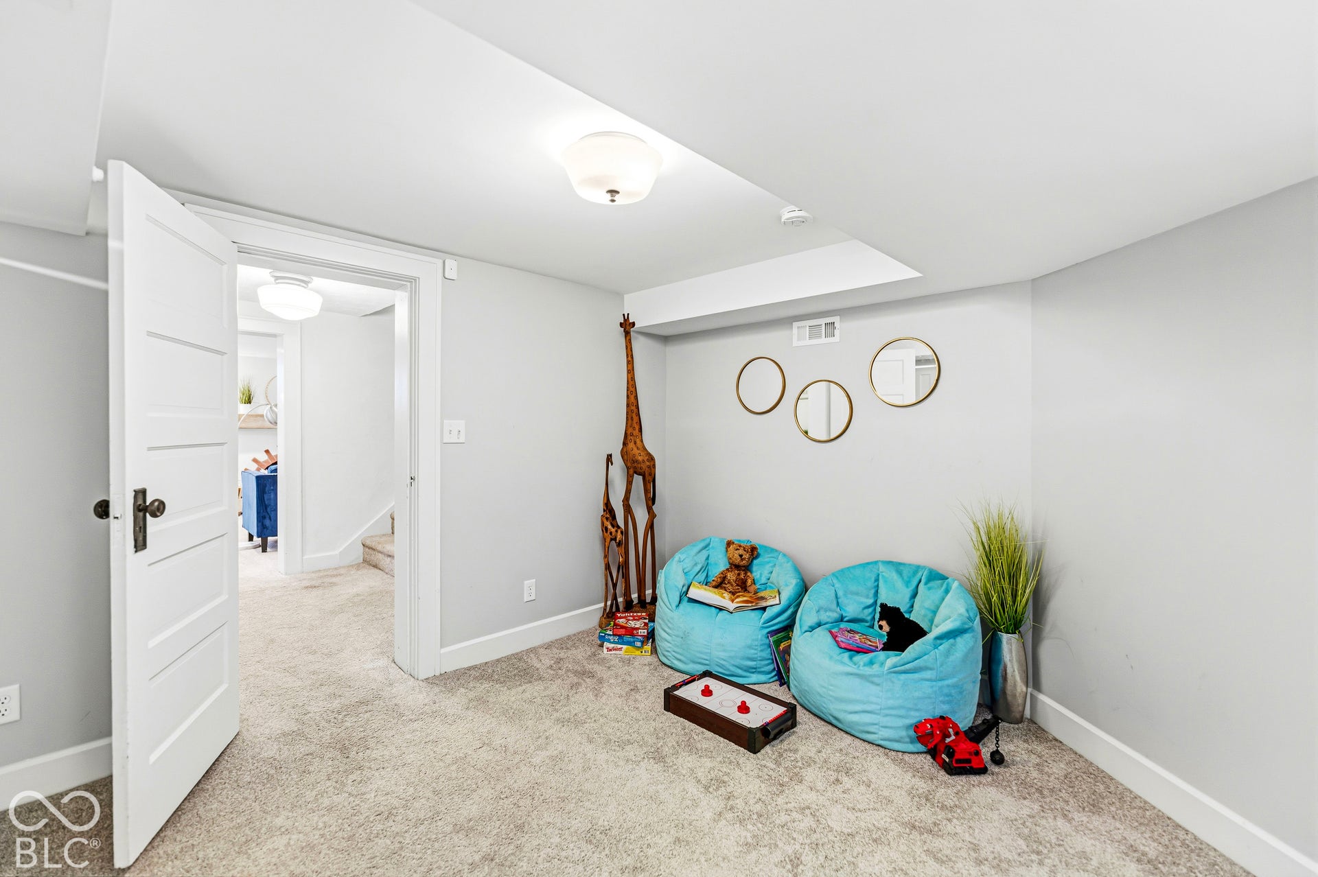 Interior room featuring neutral wall paint, wall-to-wall carpeting, a multi-panel door with oil-rubbed bronze hardware, and a flush-mount ceiling light fixture