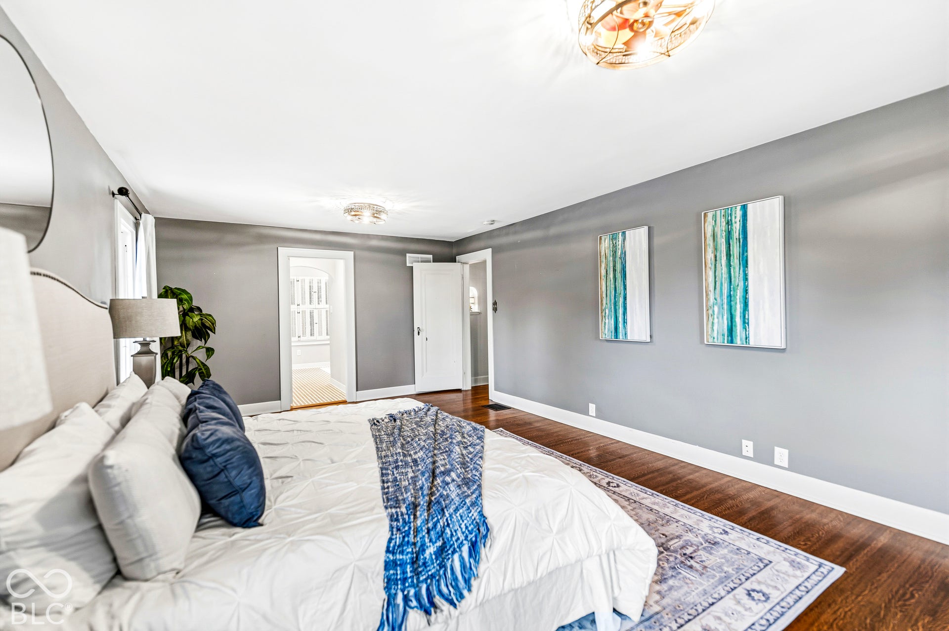 Spacious room featuring wood-finish flooring, neutral wall tones, and two glass-paneled ceiling light fixtures