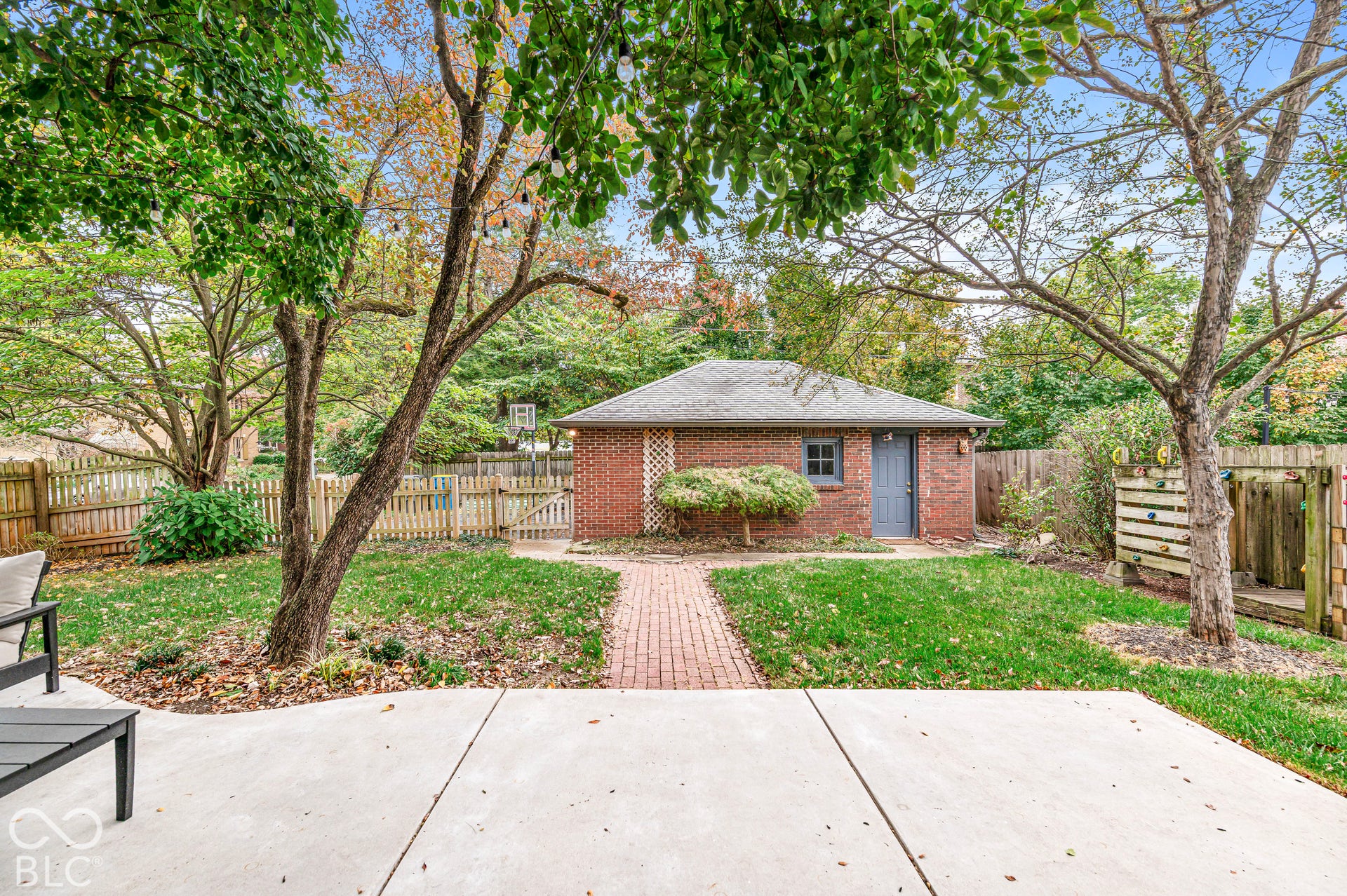Backyard featuring a brick-exterior detached garage, paved patio, brick walkway, and perimeter wood fencing