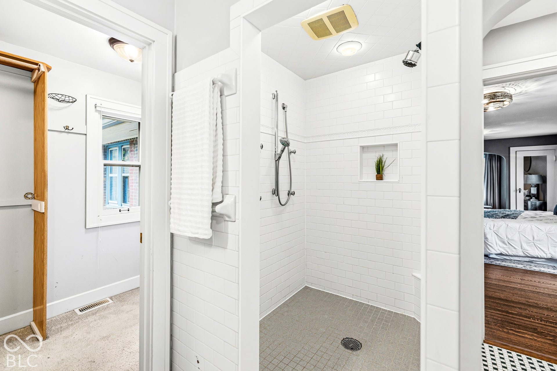 Walk-in shower featuring white subway tile surround, integrated wall niche, handheld shower fixture, and tiled flooring