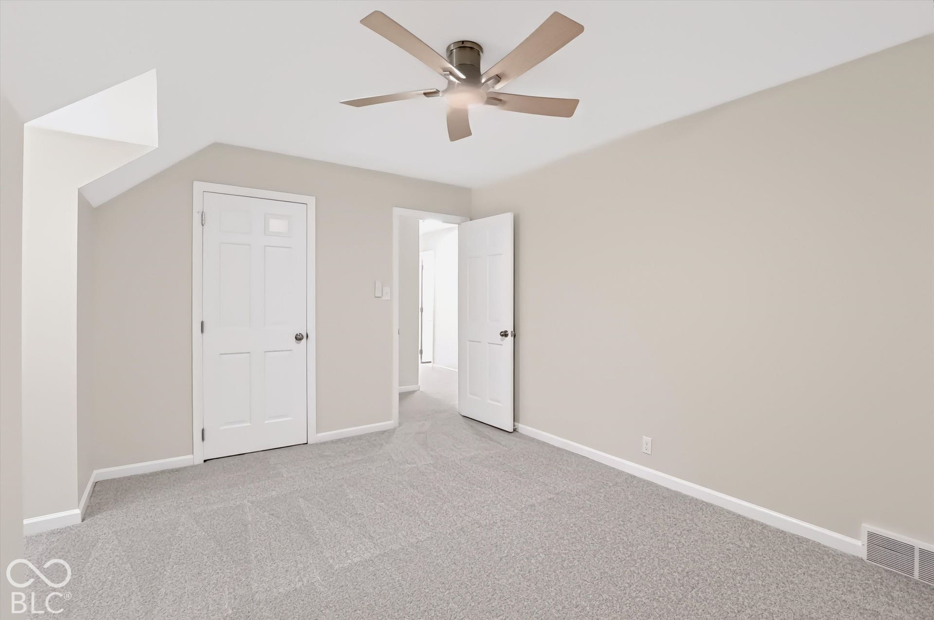 Neutral-toned interior featuring wall-to-wall carpeting, a flush-mounted ceiling fan with light fixture, and classic six-panel doors