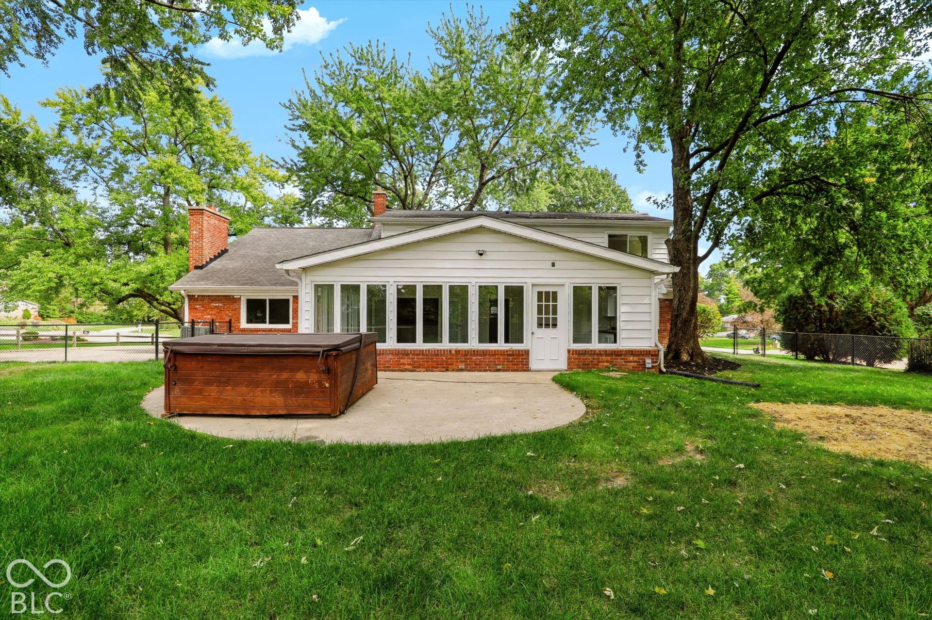 Exterior featuring a concrete patio, brick and horizontal siding facade, multiple large windows, and a chimney