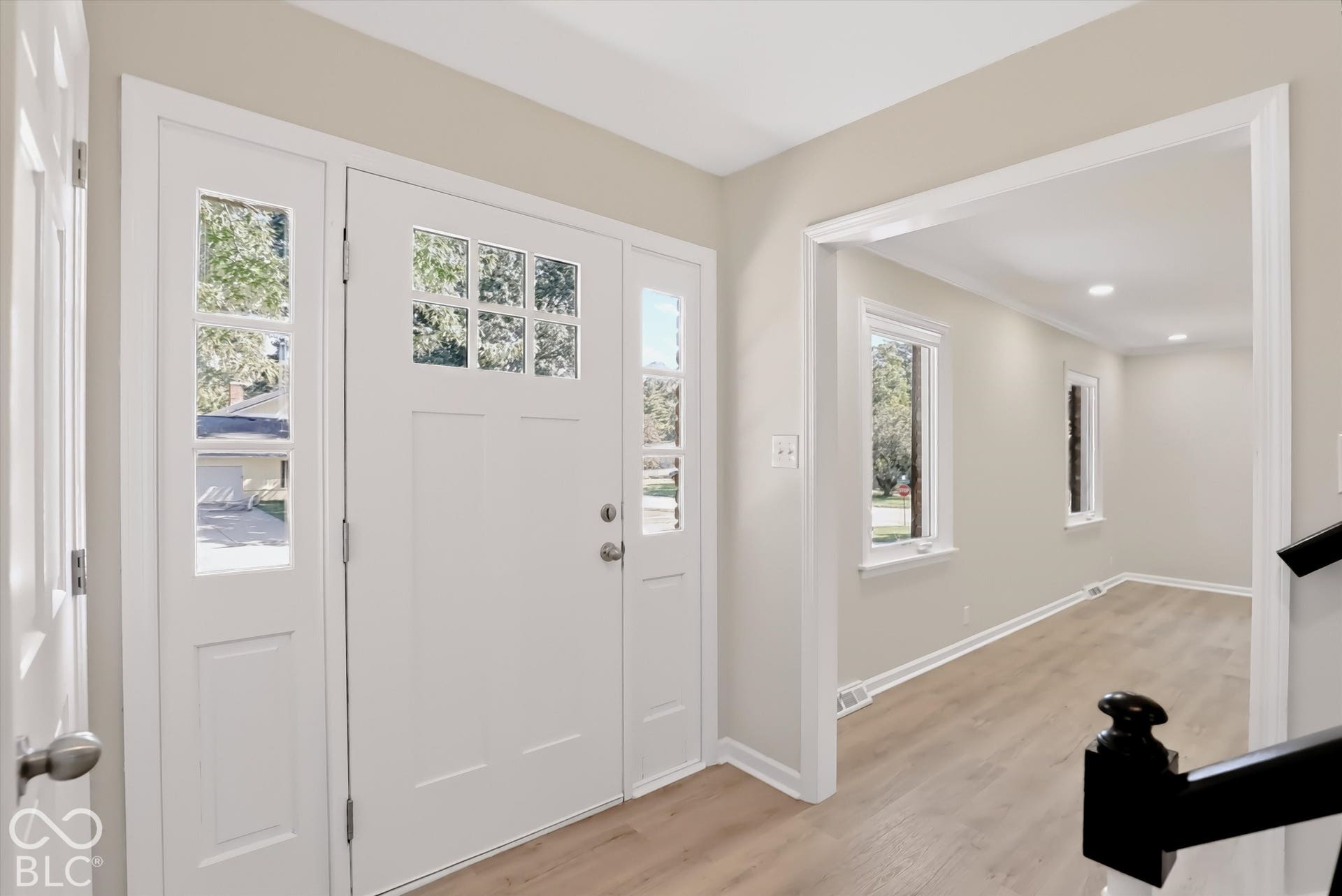 Entryway featuring a white door with glass light panels, side-light windows, neutral paint, wood-finish flooring, and recessed ceiling lighting