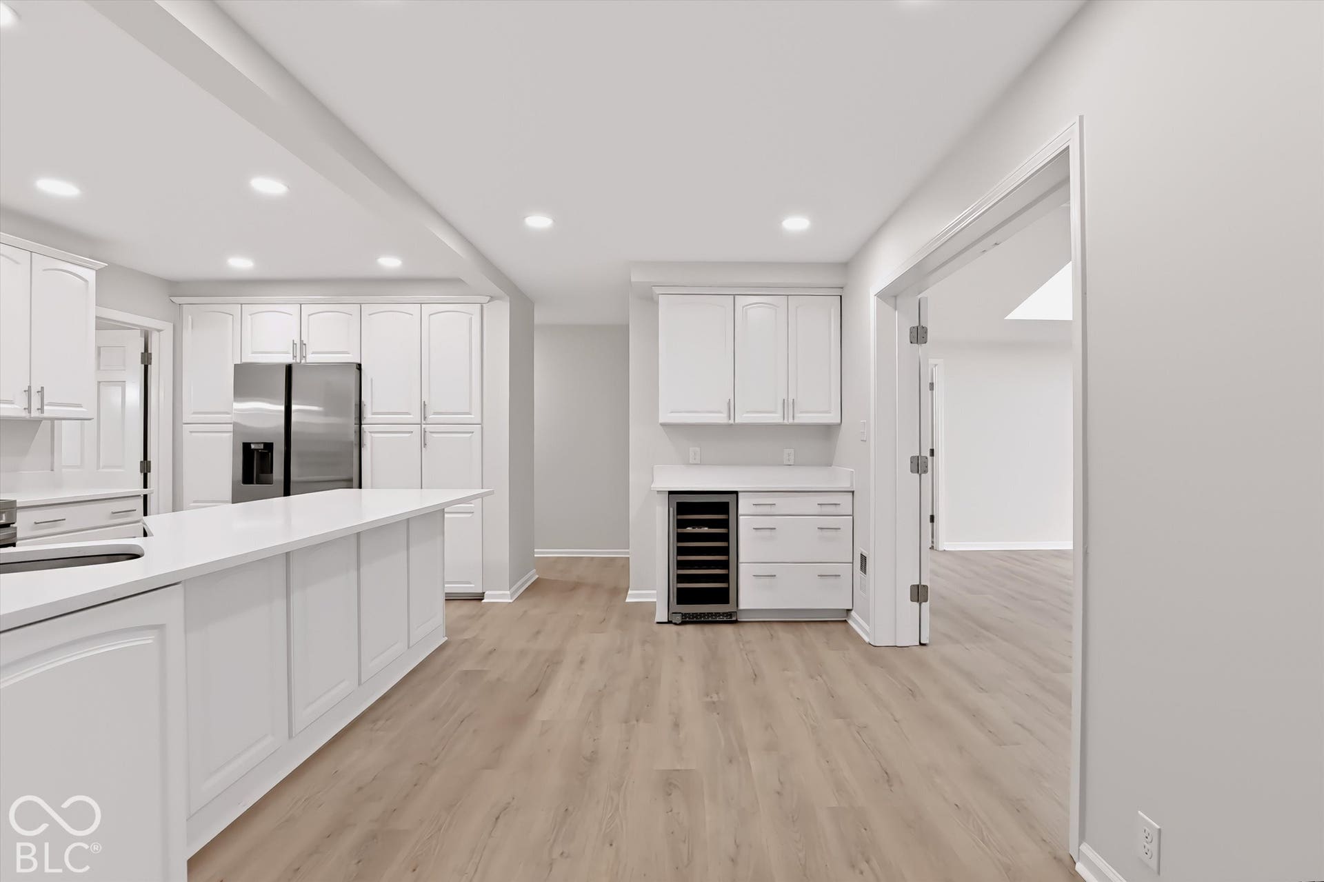 Kitchen featuring white cabinetry, wood-finish flooring, recessed lighting, stone-surface countertops, and a built-in wine refrigerator