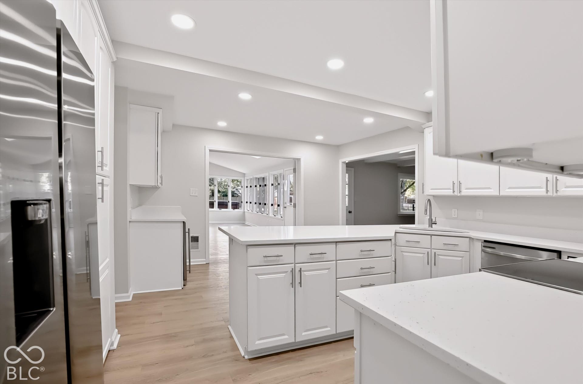 Kitchen featuring white shaker-style cabinetry, quartz countertops, a central island, recessed lighting, and wood-finish flooring