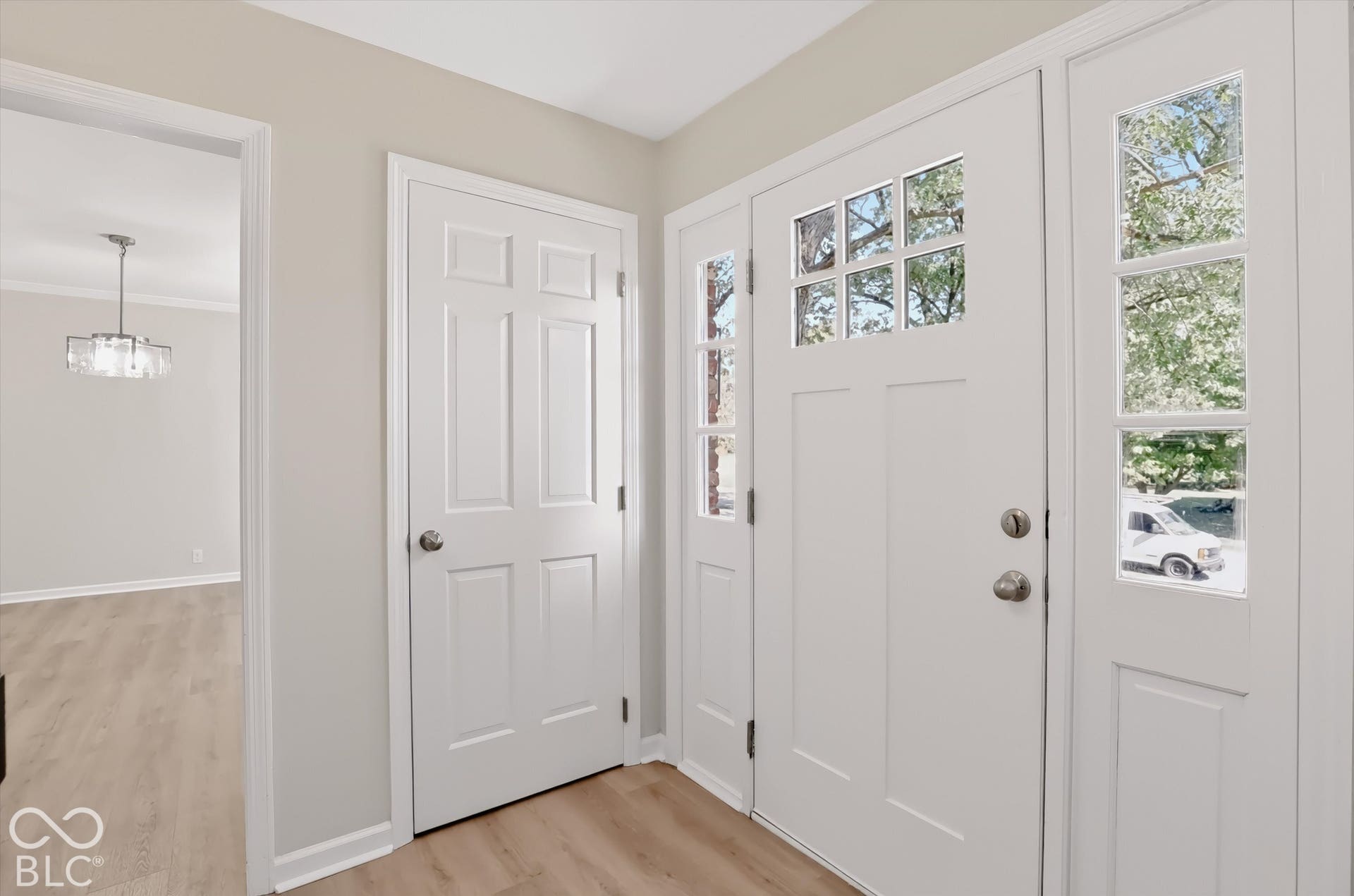 Entryway featuring a white door with glass panes, sidelight windows, six-panel interior door, and wood-finish flooring
