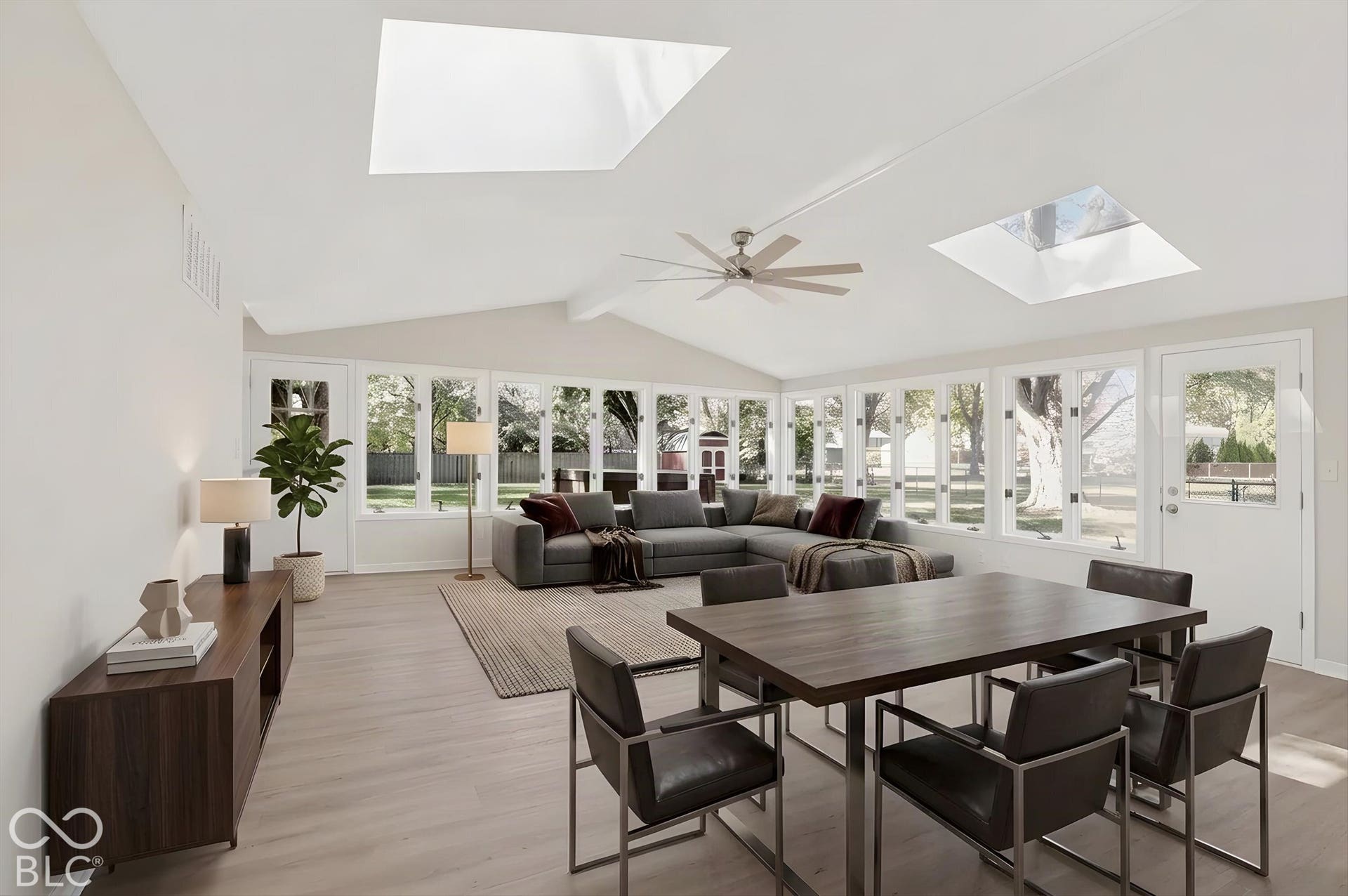 Virtually Altered - Vaulted ceiling featuring two skylights, neutral wall finish, wood-finish flooring, and a multi-blade ceiling fan