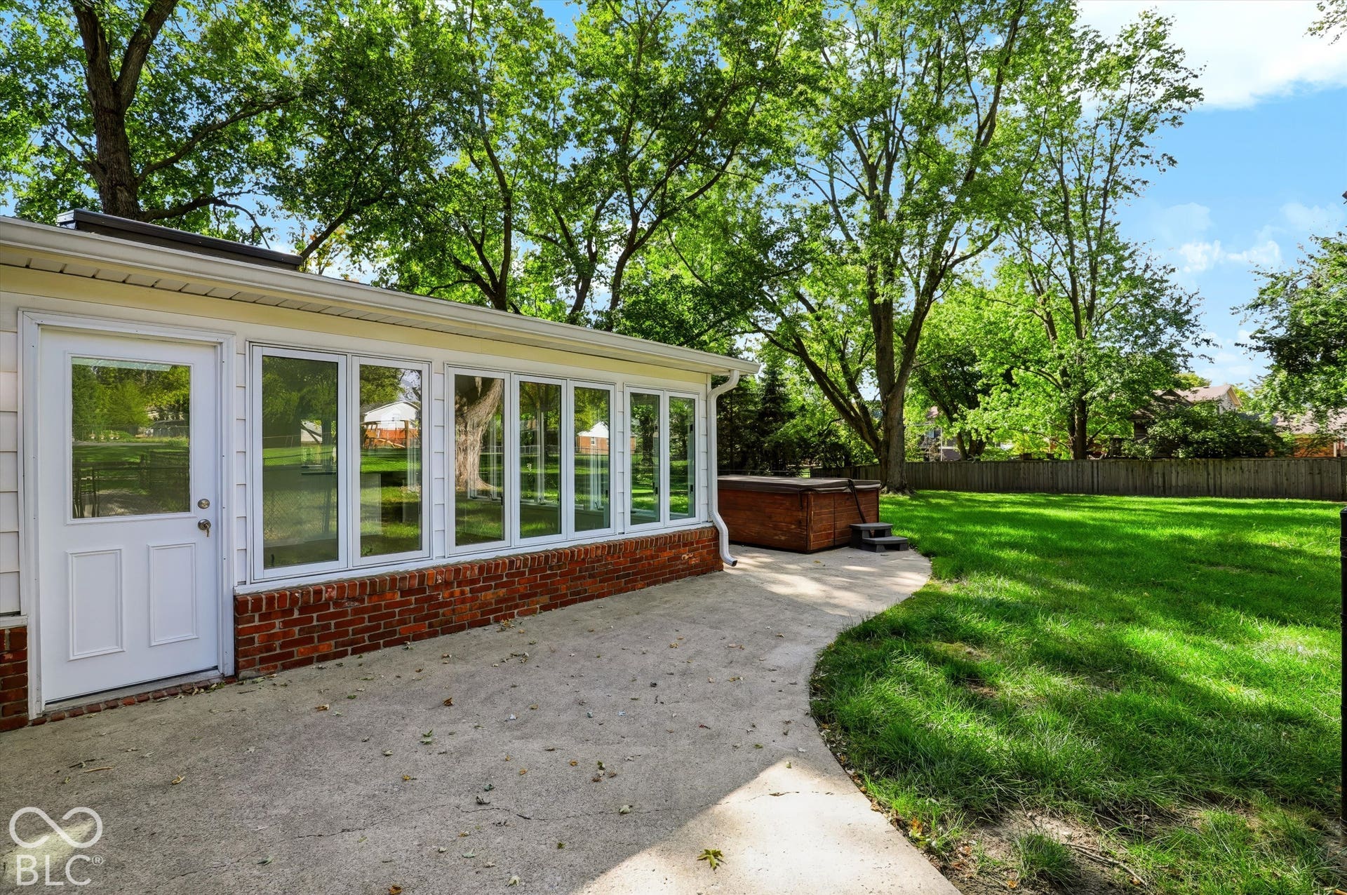 Sunroom exterior featuring brick masonry base, white-framed windows, and a paved concrete patio