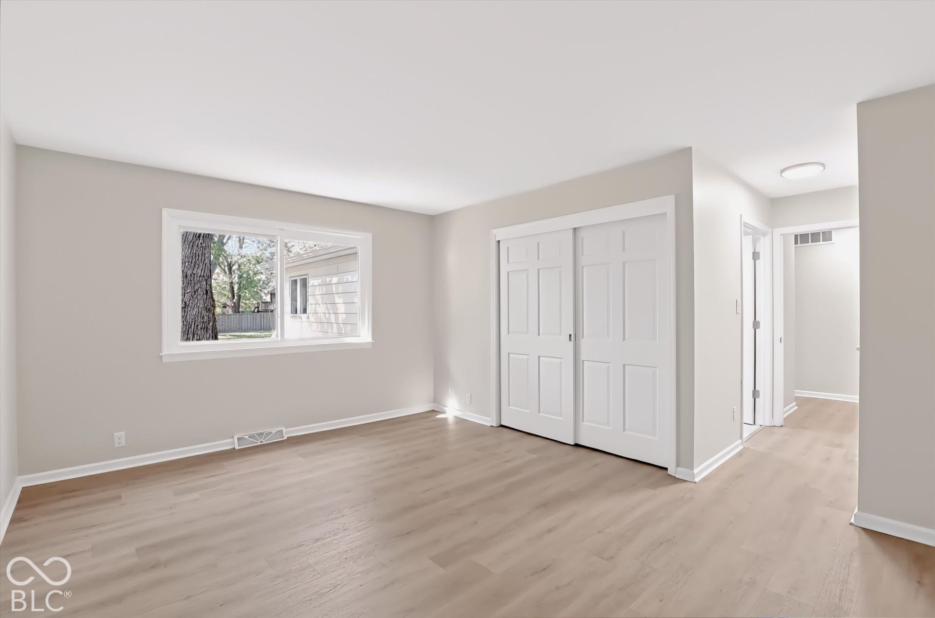 Neutral-toned walls, wood-finish flooring, and sliding closet doors with paneled detailing