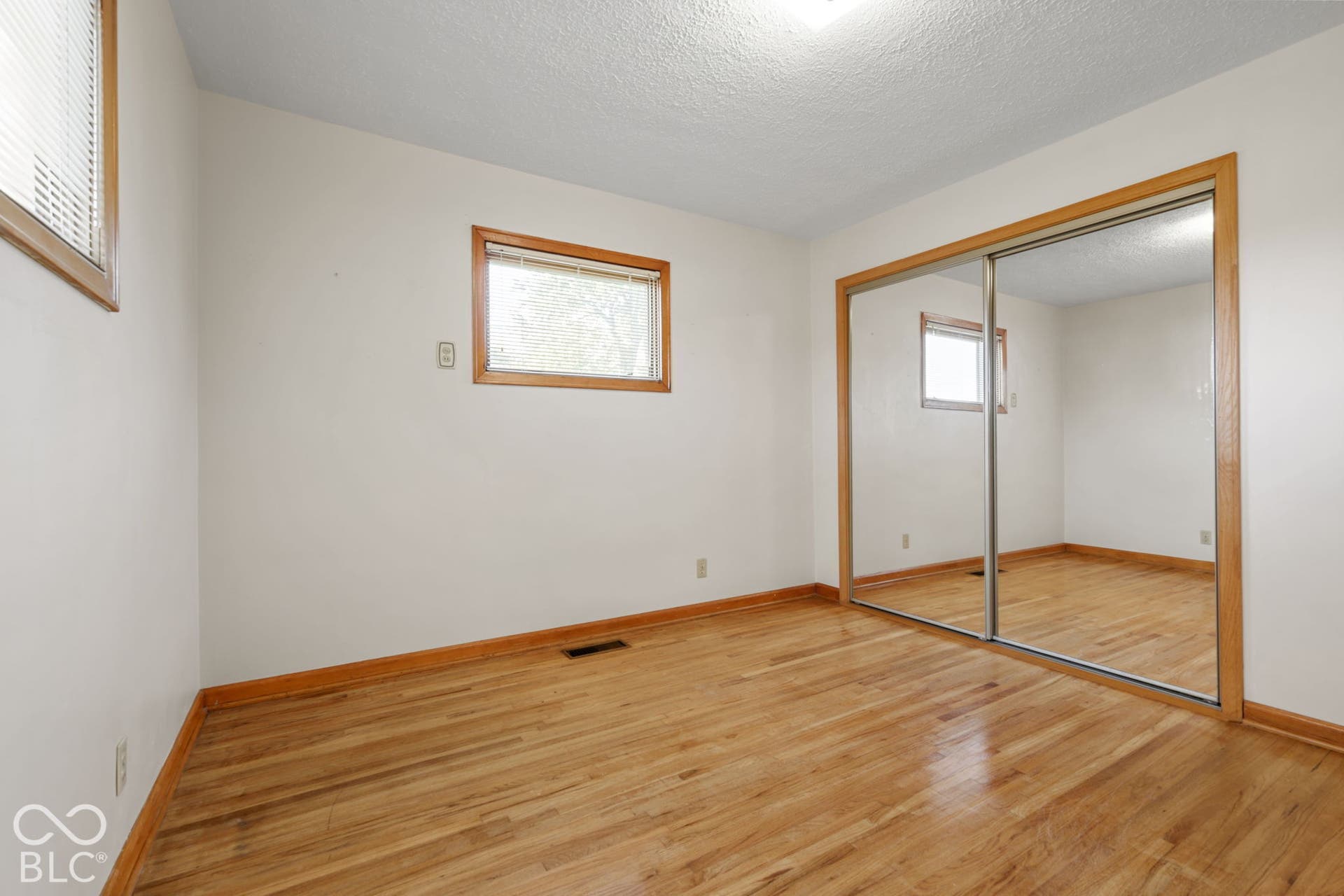 280 Anniston, Indianapolis, IN 46227 Room interior featuring wood-finish flooring, wood-framed windows, and a sliding mirrored closet door