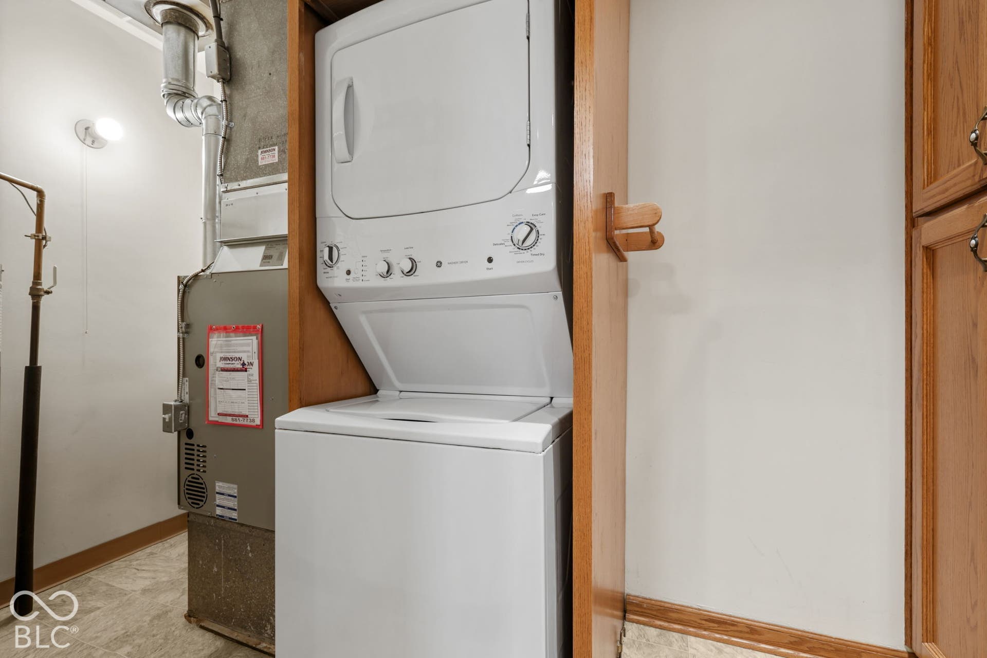280 Anniston, Indianapolis, IN 46227 Stacked laundry unit housed within wood-finish cabinetry, featuring a dedicated furnace, wall-mounted light fixture, and tile flooring