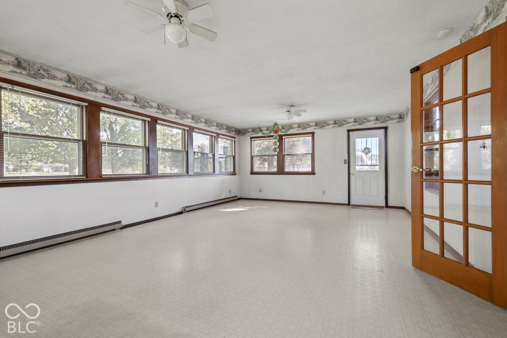 280 Anniston, Indianapolis, IN 46227 Sunroom featuring wood-trim windows, two ceiling fans, grid-patterned glass-pane door, and resilient flooring