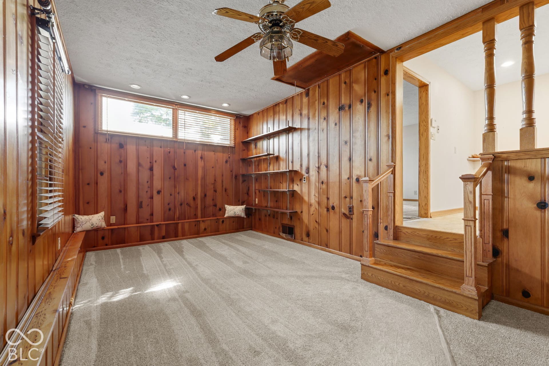 280 Anniston, Indianapolis, IN 46227 Interior featuring vertical wood paneling, built-in shelving, a tiered staircase with a wooden balustrade, and a ceiling fan