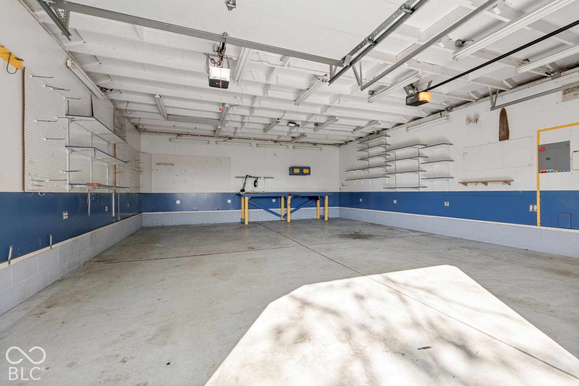 280 Anniston, Indianapolis, IN 46227 Multi-car garage featuring a concrete floor, built-in workbench, extensive wall-mounted shelving, and dual automated door openers