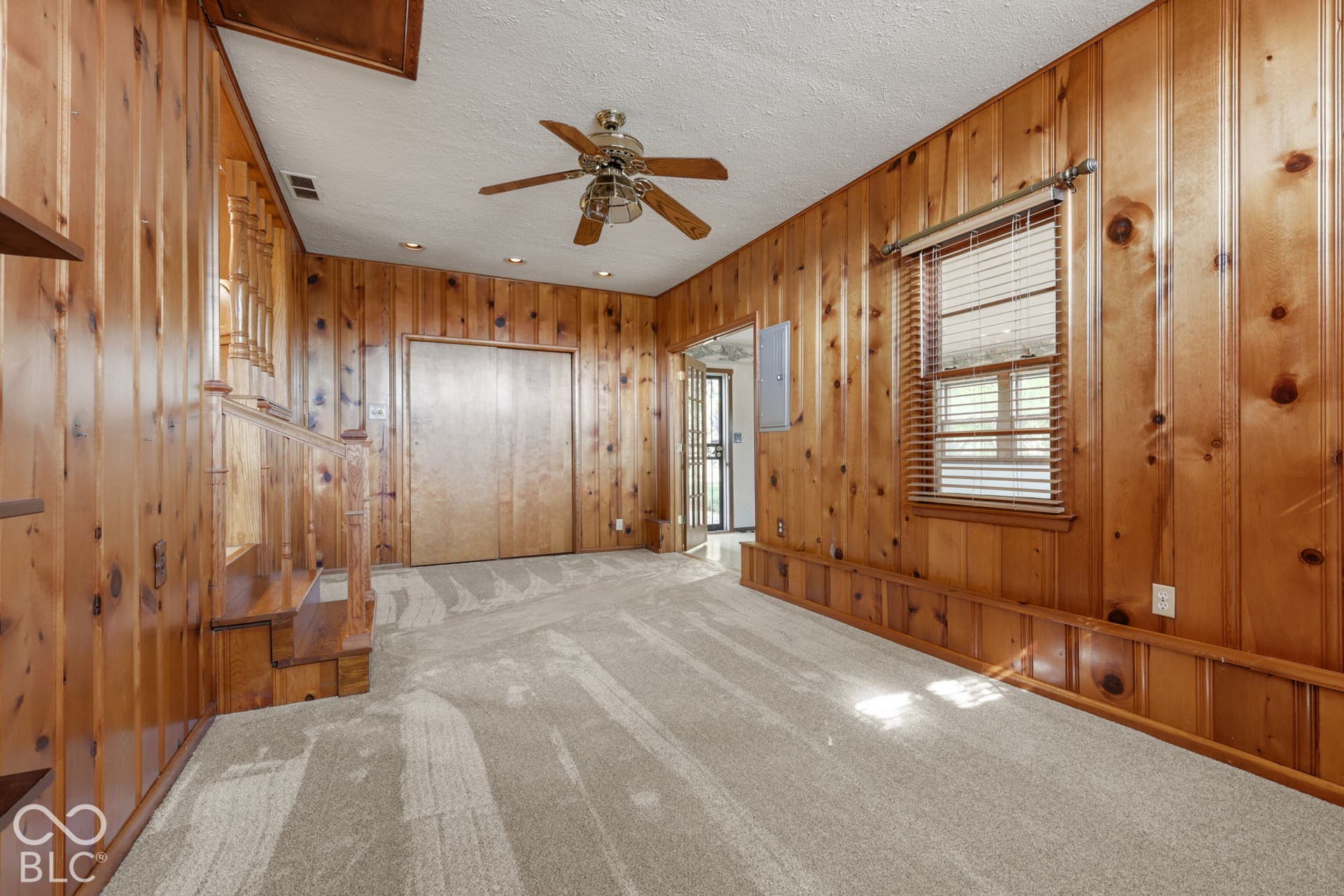 280 Anniston, Indianapolis, IN 46227 Knotty pine wood paneling, carpeted flooring, built-in closet with sliding doors, multi-speed ceiling fan with integrated lighting, and wood-framed window with blinds