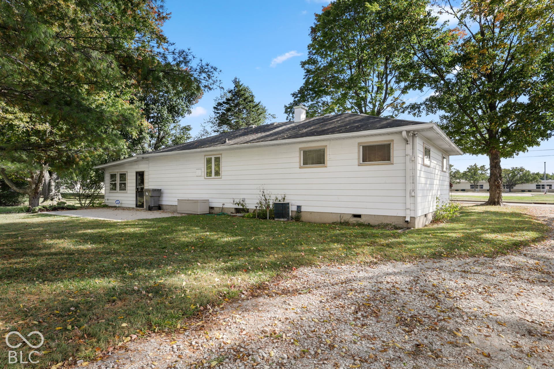 280 Anniston, Indianapolis, IN 46227 Exterior featuring horizontal siding, a concrete patio, and a gravel driveway set amidst mature trees