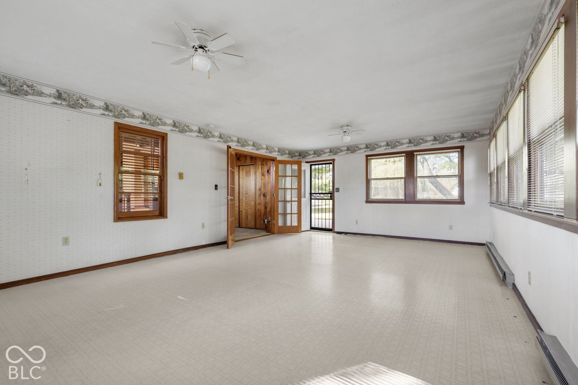 280 Anniston, Indianapolis, IN 46227 Spacious room featuring multiple windows with integrated blinds, two ceiling fans, wood-frame glass panel doors, and neutral textured flooring