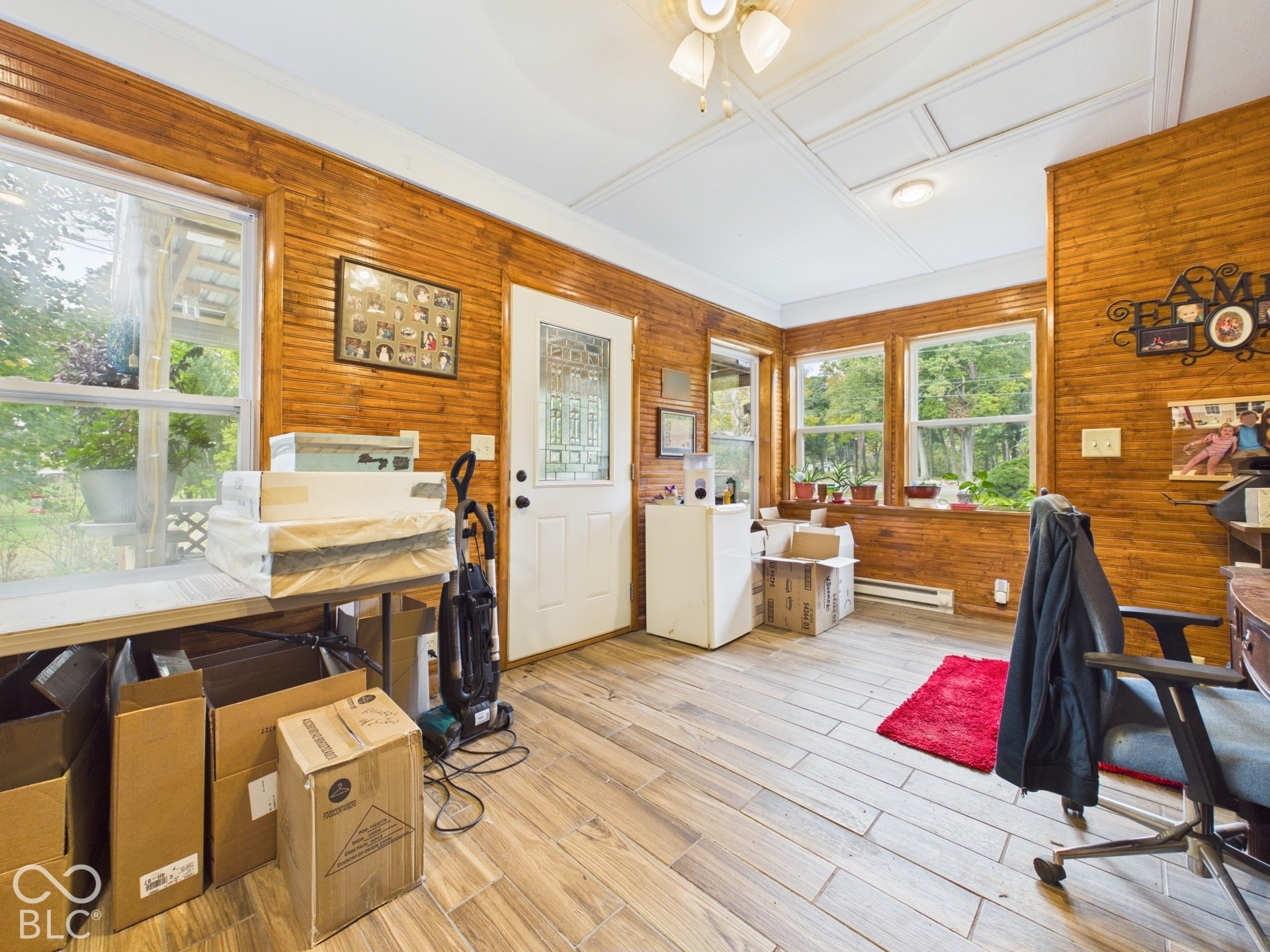 Room featuring wood-plank wall paneling, wood-finish tile flooring, multiple windows, and a glass-paneled exterior door