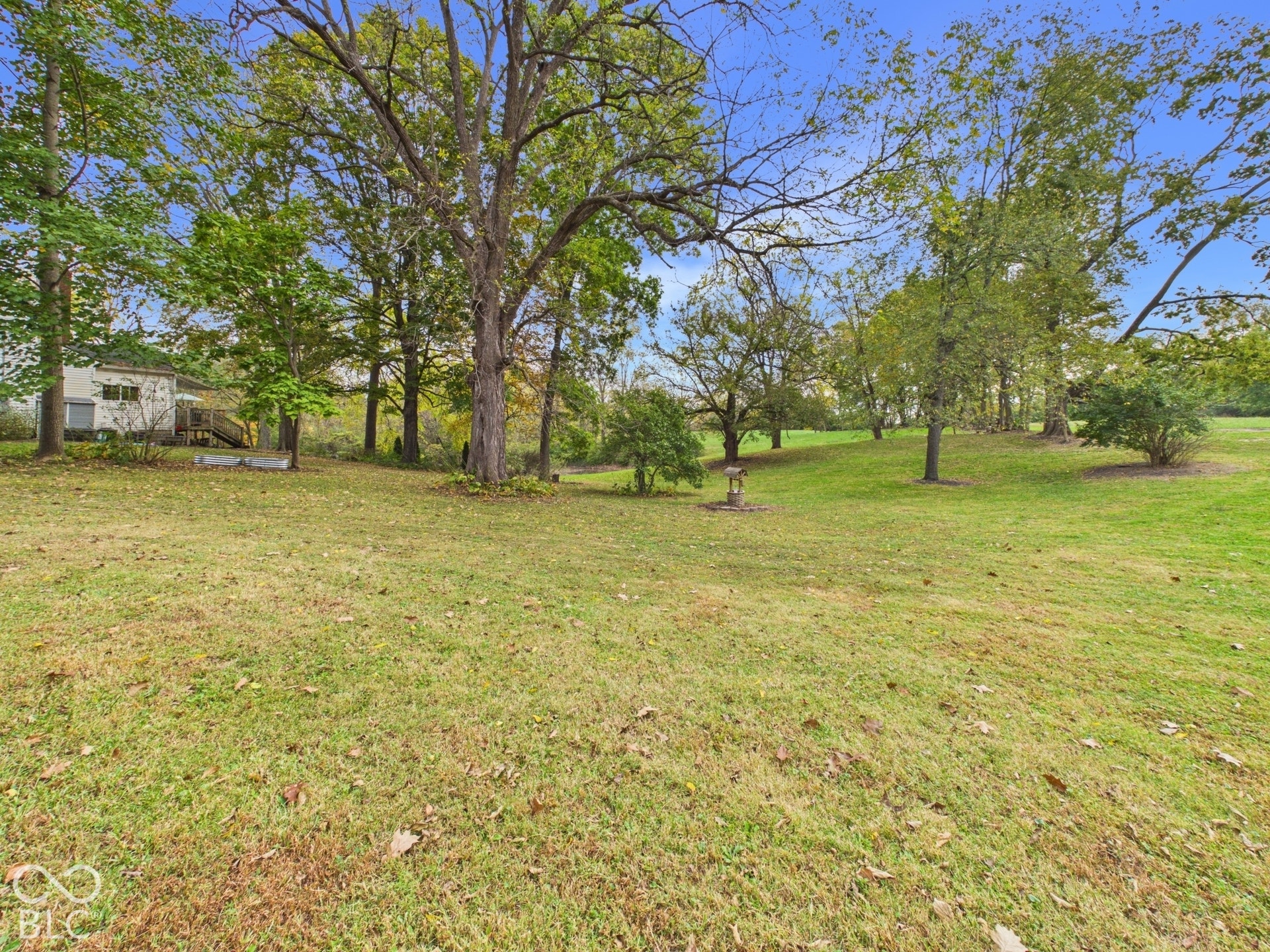 Expansive grounds featuring a vast lawn, mature trees, and a stone water feature