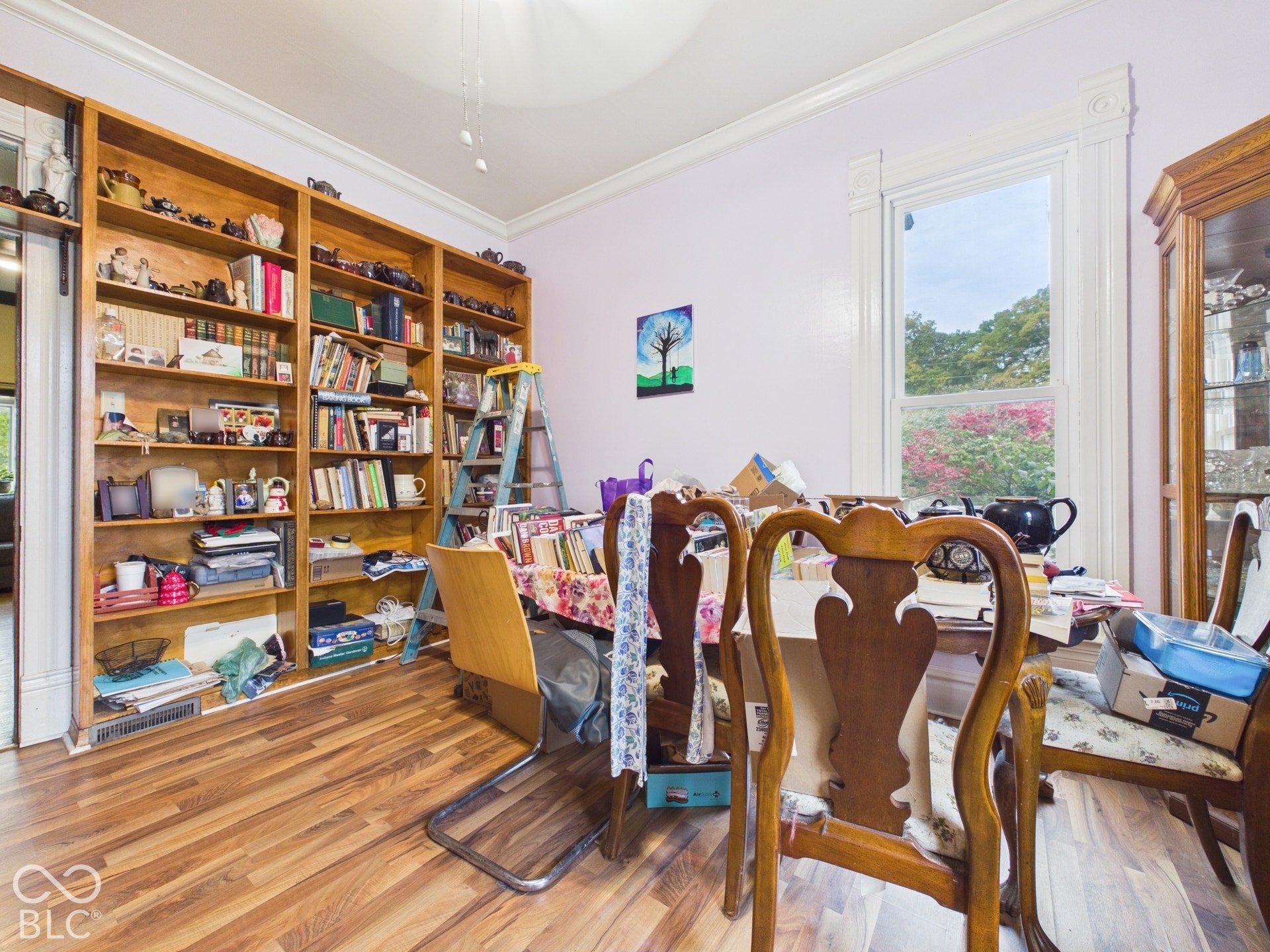 Built-in floor-to-ceiling wood shelving, crown molding, detailed window casing, and wood-finish flooring