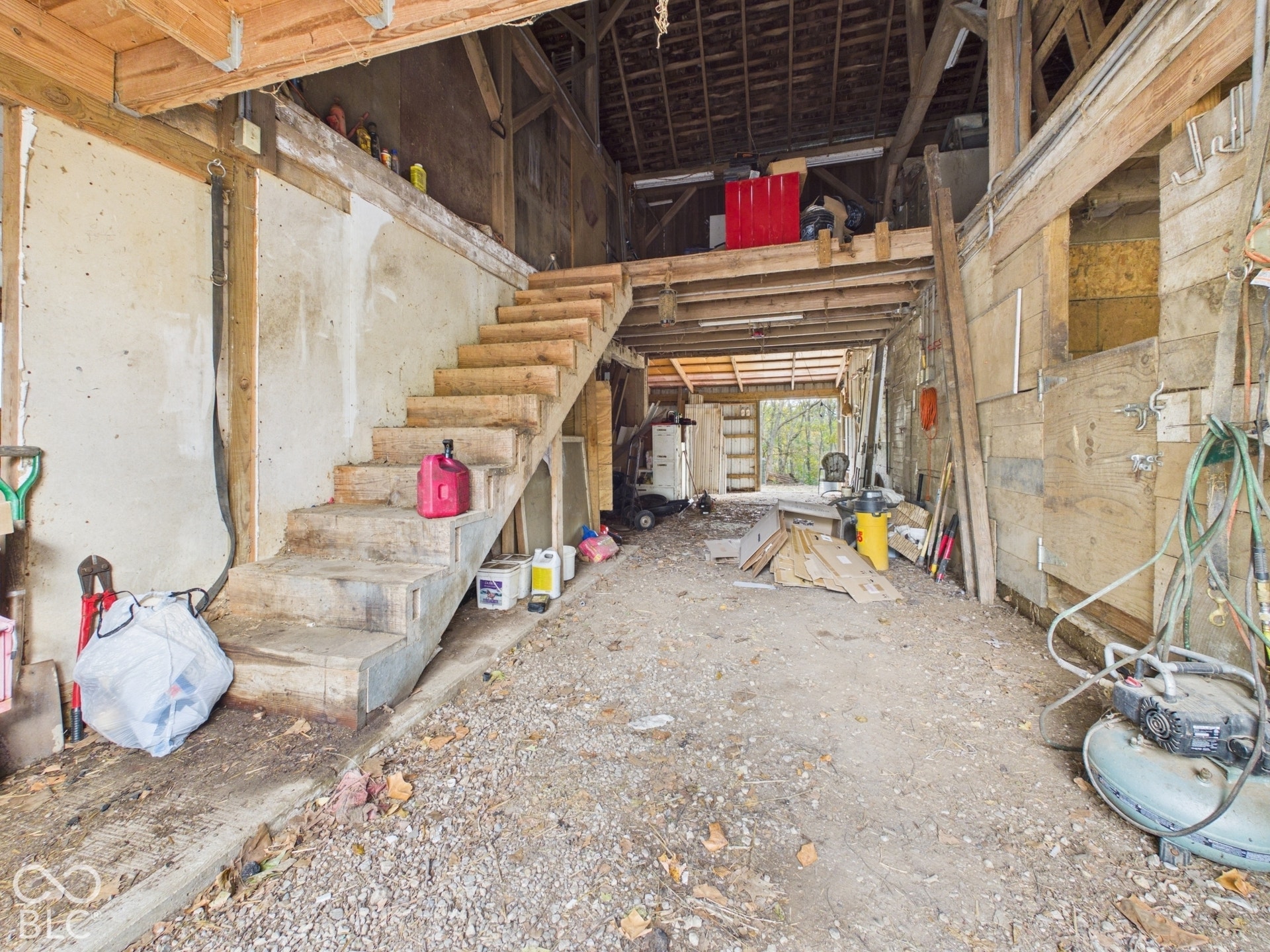 Multi-use barn structure featuring heavy timber framing, an elevated storage loft, open-staircase architecture, and stall partitioning