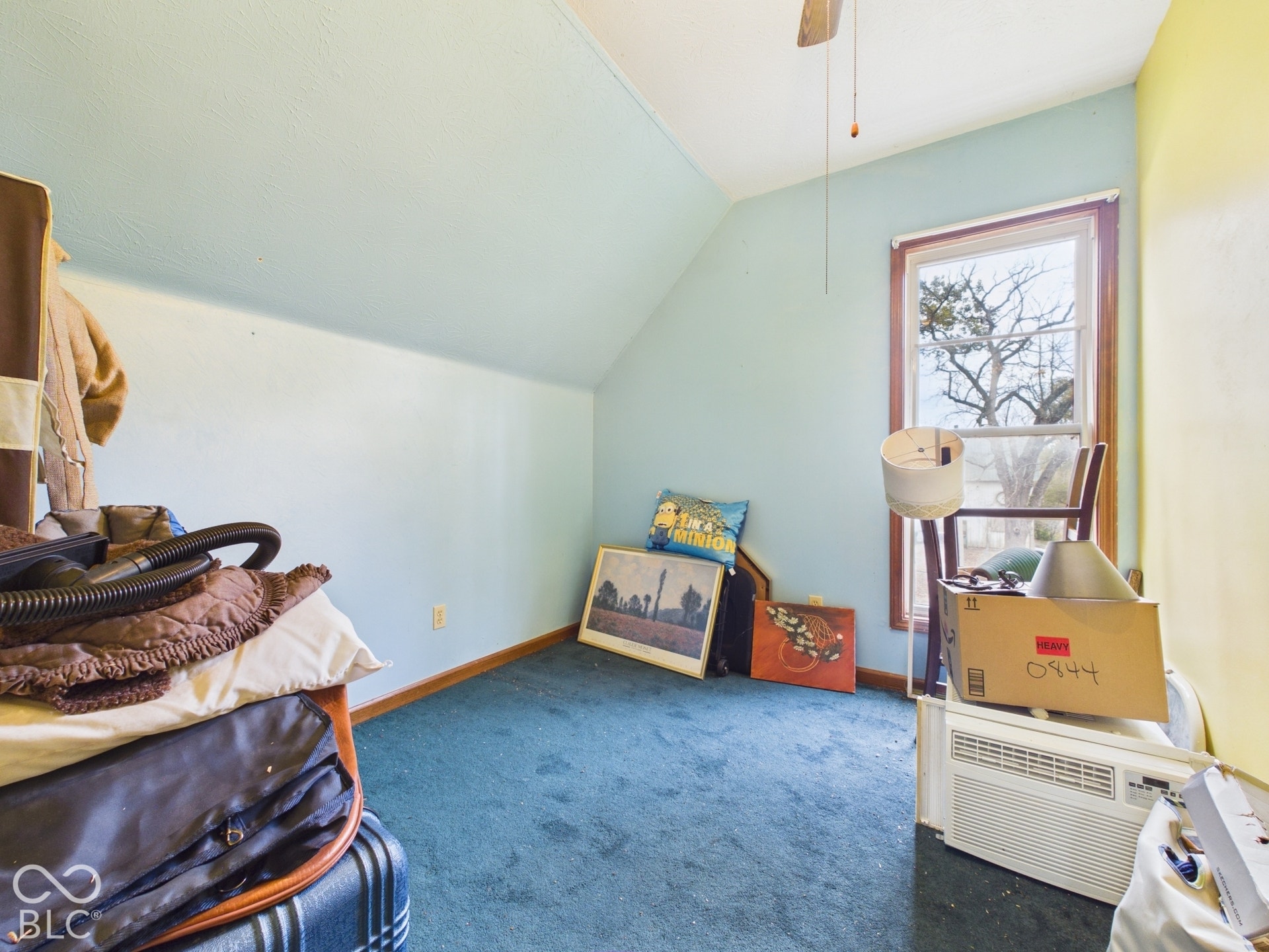Room featuring a sloped ceiling, single-pane window with wood trim, and carpeted flooring
