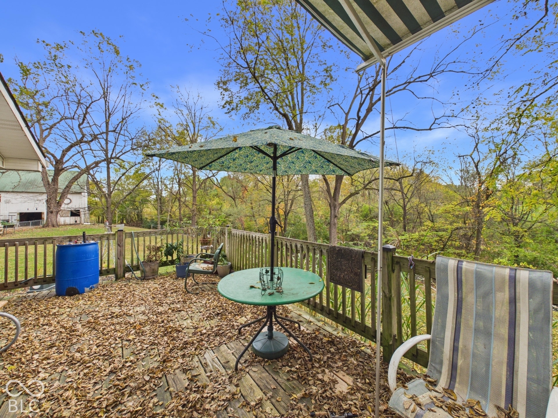 Elevated wood deck featuring vertical slat railing, retractable fabric awning, and wood-plank flooring