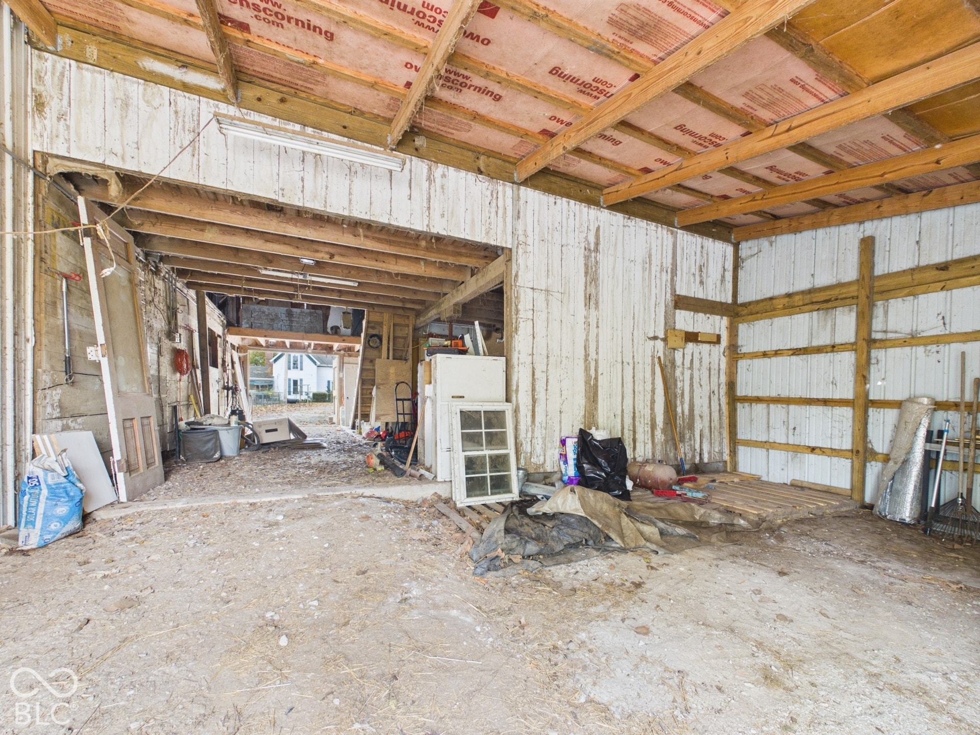 Pole barn structure featuring exposed timber framing, vertical board siding, and an open-concept interior layout with an earthen floor