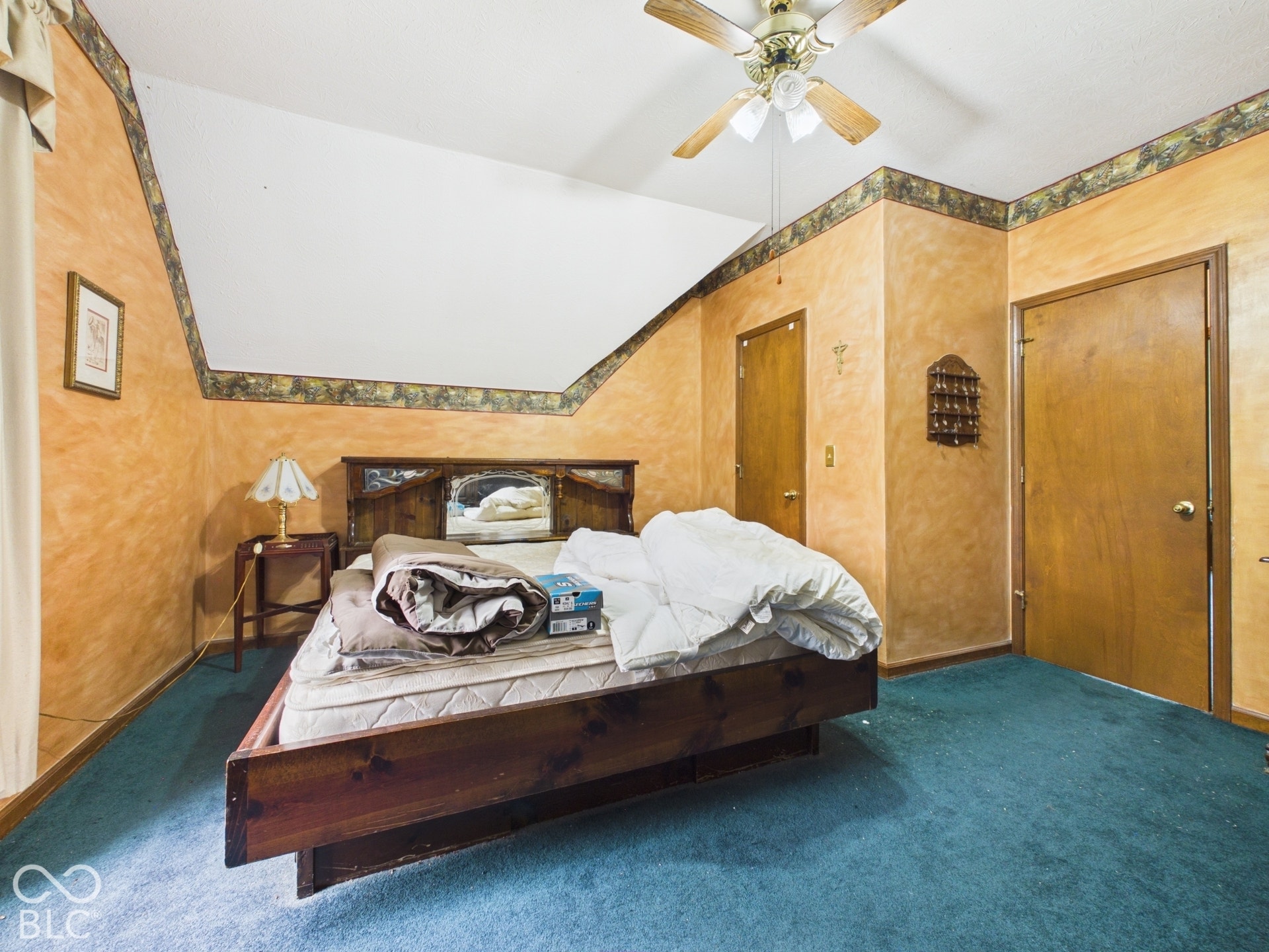 Sloped ceiling with decorative border trim, textured wall finish, and overhead ceiling fan with integrated lighting
