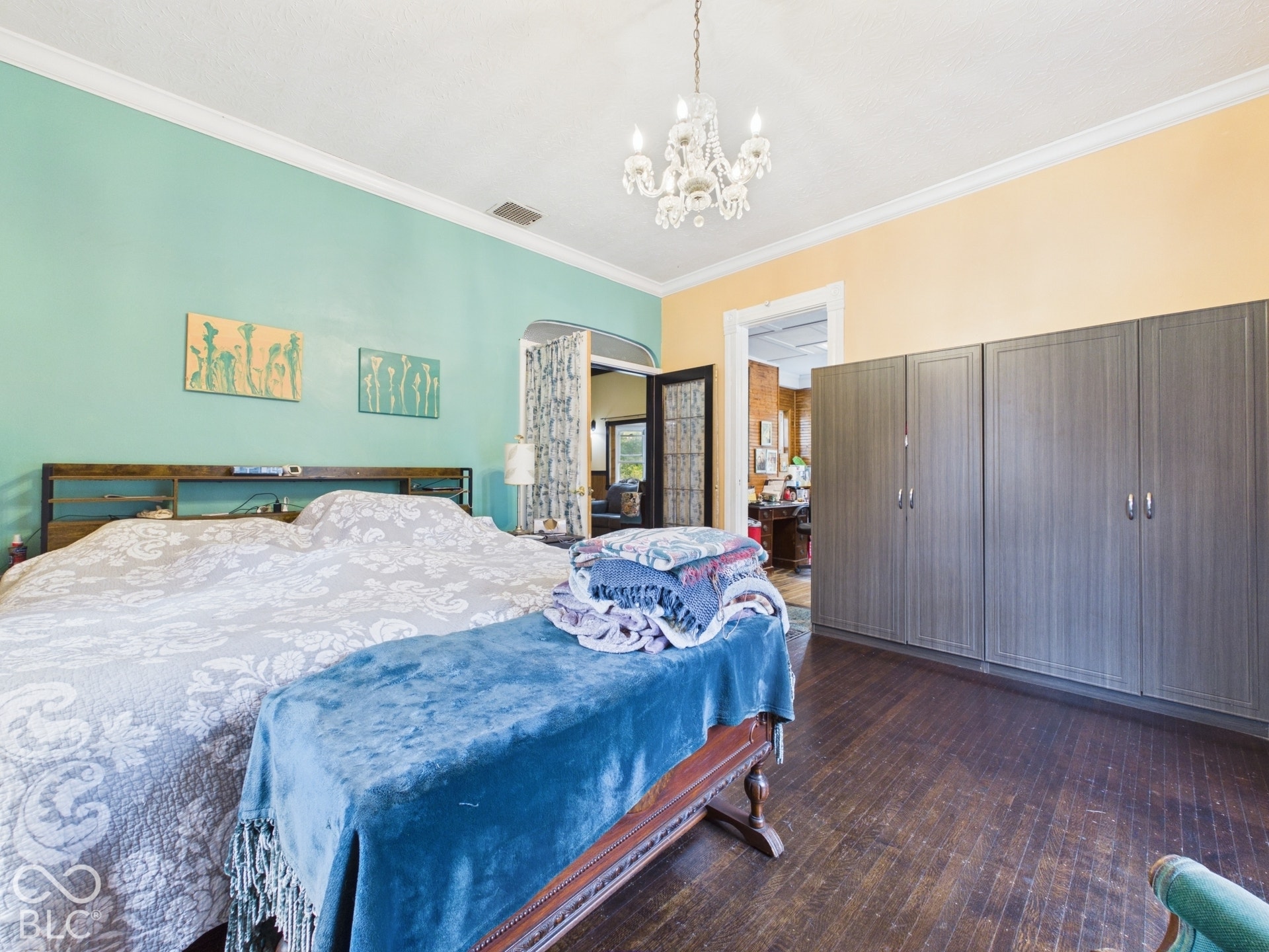 Dark-stained hardwood flooring, floor-to-ceiling built-in cabinetry, crown molding, and a tiered crystal chandelier