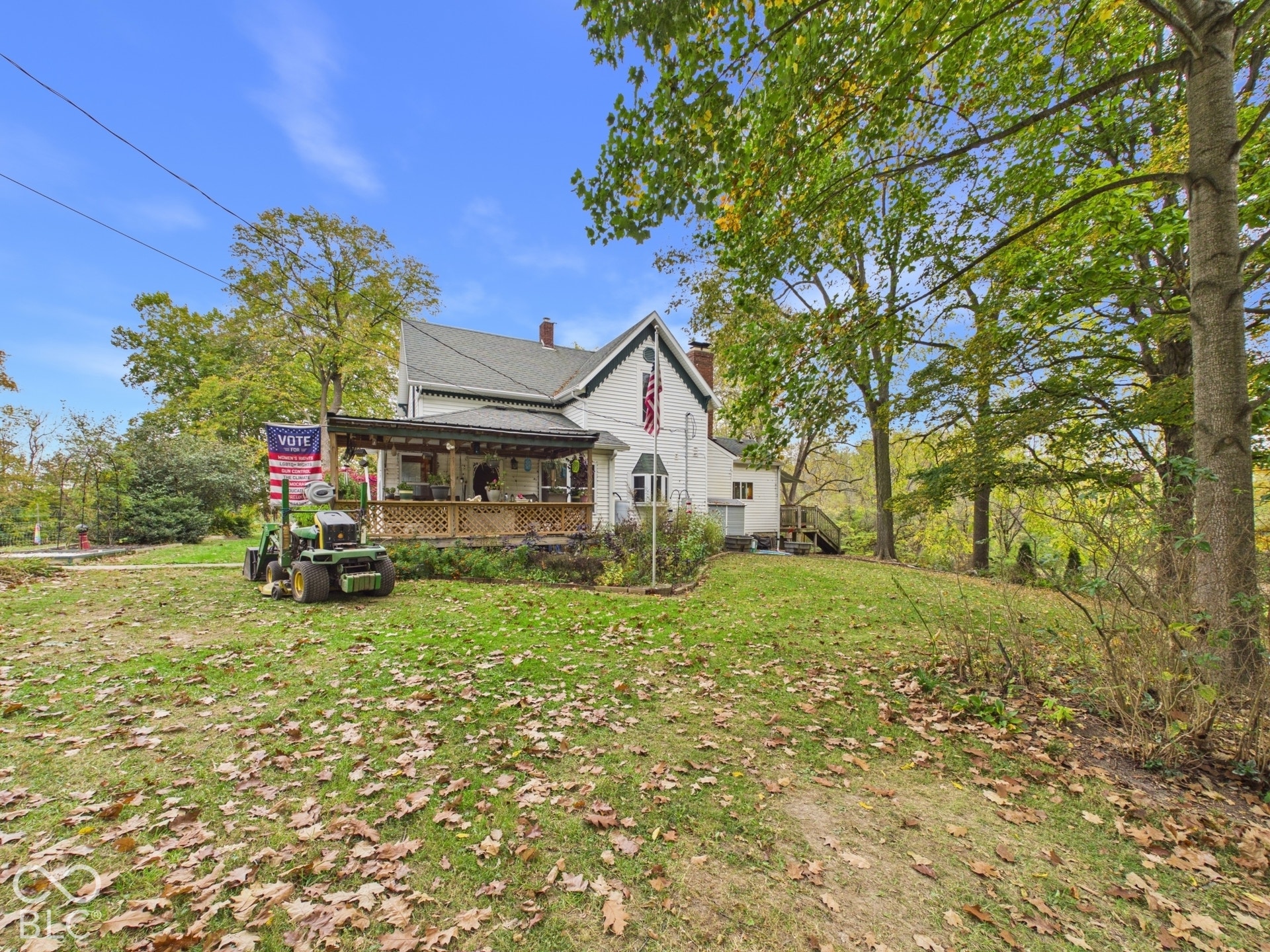 Two-story residence with a gabled roof, covered porch, masonry chimney, and expansive wooded lot