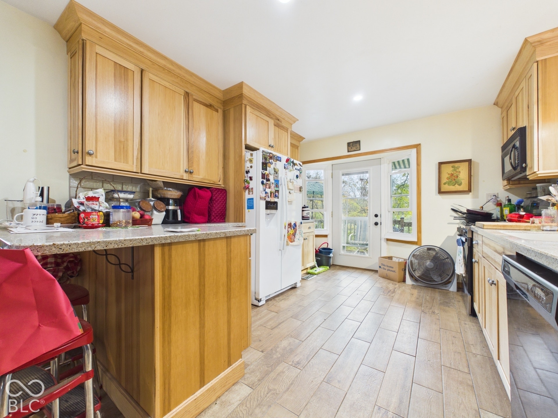 Kitchen featuring light wood cabinetry with crown molding, stone-finish countertops, wood-finish tile flooring, and a glass-paneled exterior door