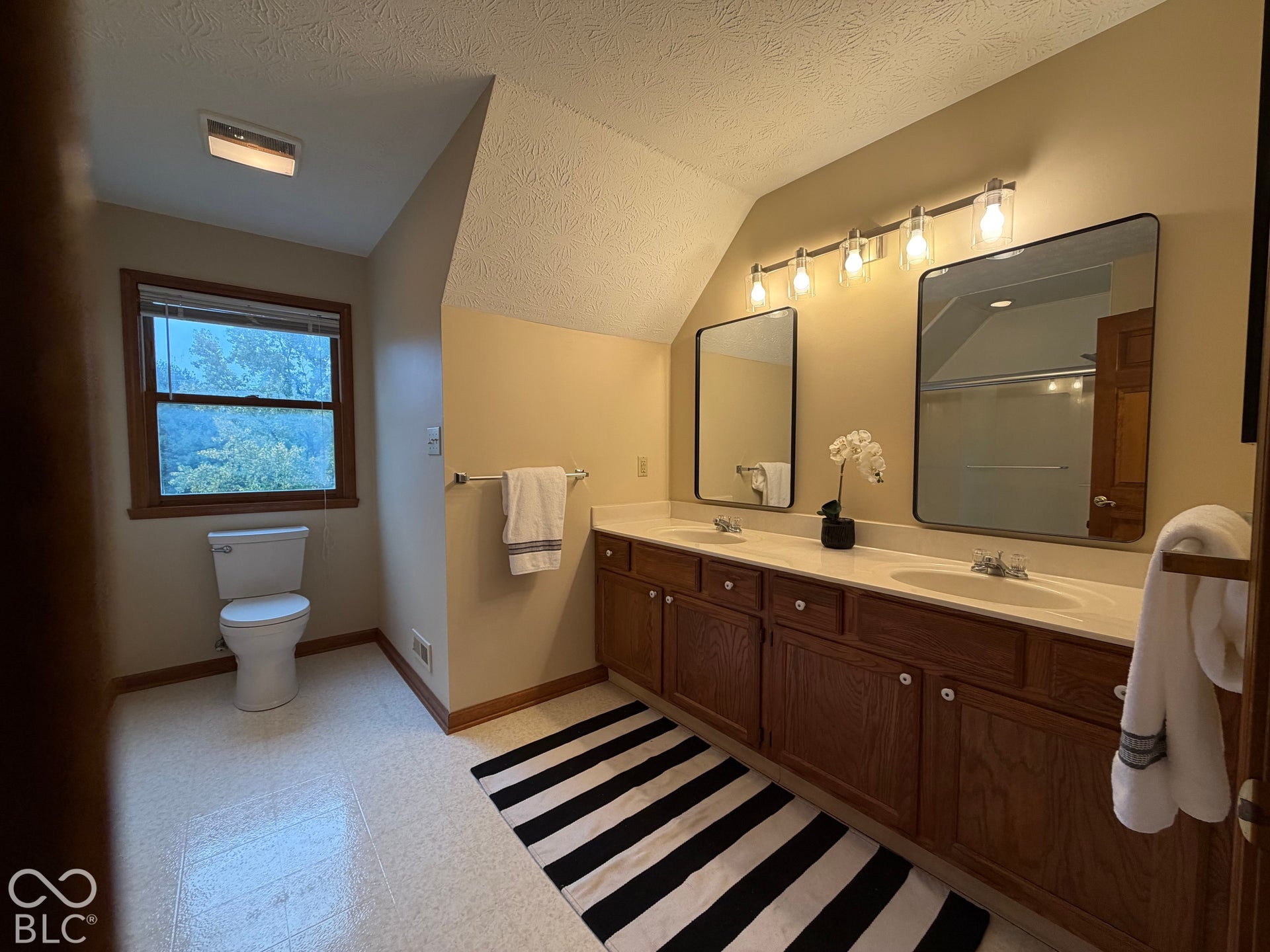 Hall bath with spacious vanity with two sinks, beautiful mirrors and upscale lighting. Over here we take our bathrooms seriously! There's even a spacious linen closet.