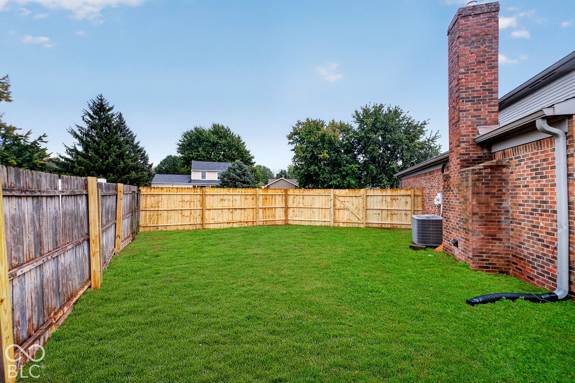 Private backyard featuring a manicured lawn, full wood fencing, and an exposed brick chimney