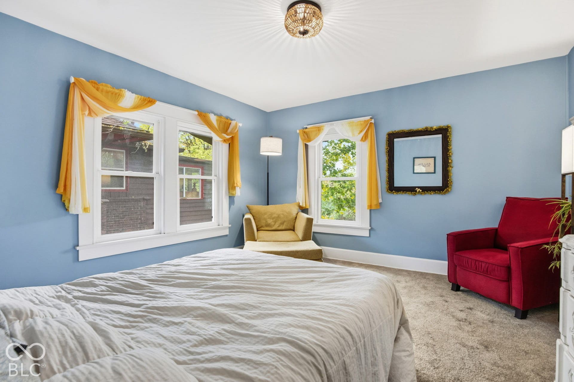 Neutral-toned carpeting, triple-window configuration with white millwork, and a flush-mount drum ceiling fixture