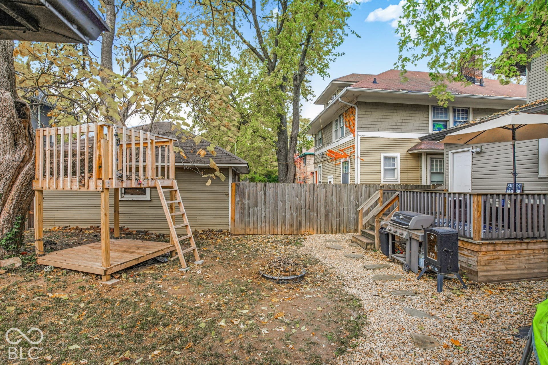 Private outdoor space featuring a raised wooden platform structure, wood decking, stone ground cover, and wood perimeter fencing