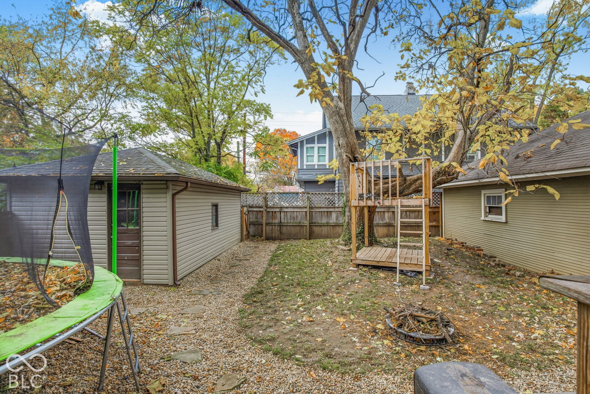Fenced backyard featuring a gravel path, a detached garage, and mature trees