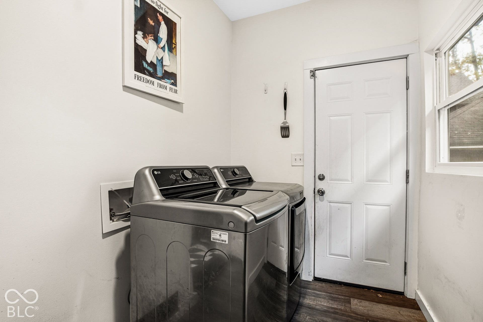 Utility area featuring wood-finish flooring, a six-panel exterior door, and a single-hung window