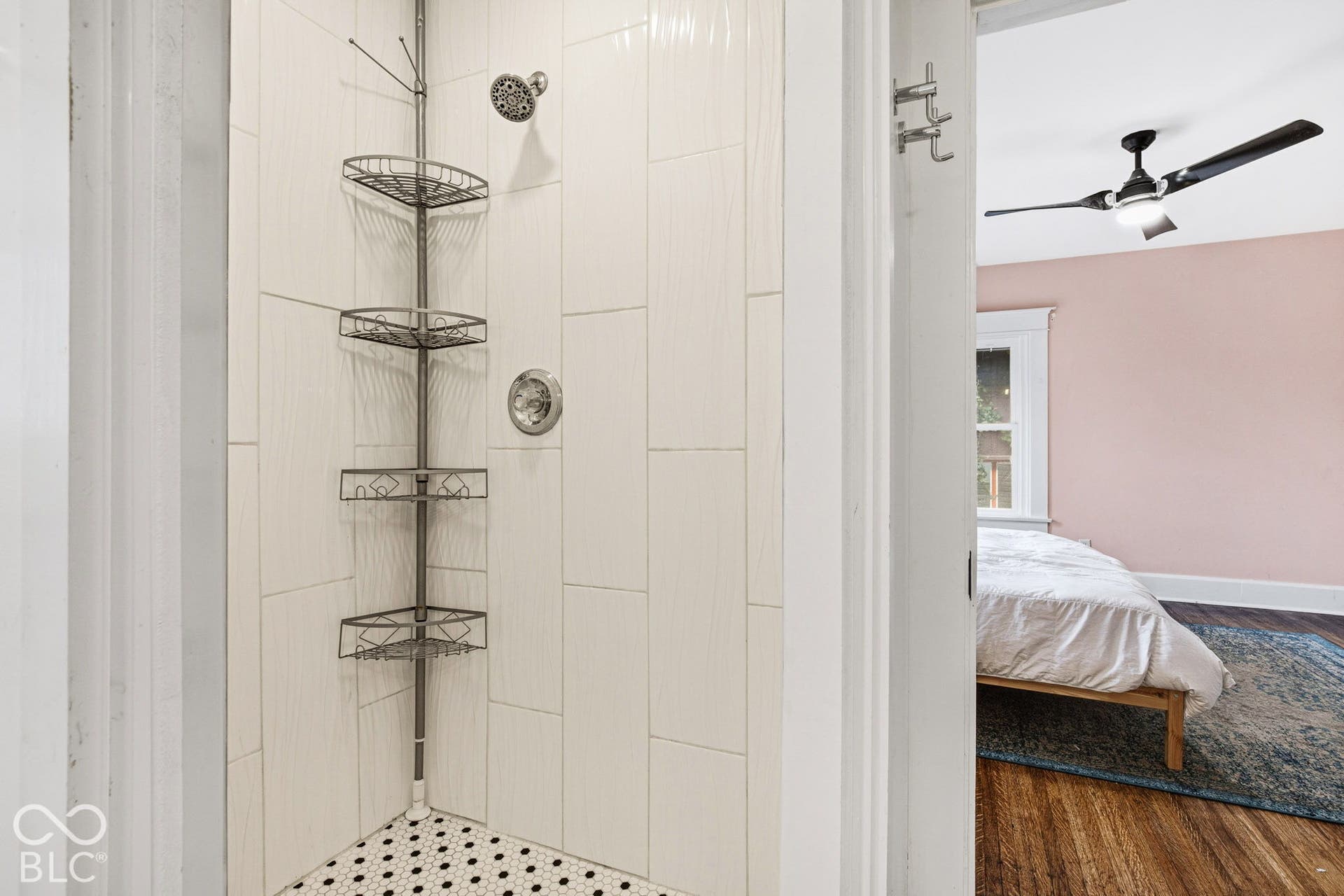 Shower stall featuring vertical rectangular wall tile, hexagonal floor tile, and a circular shower head