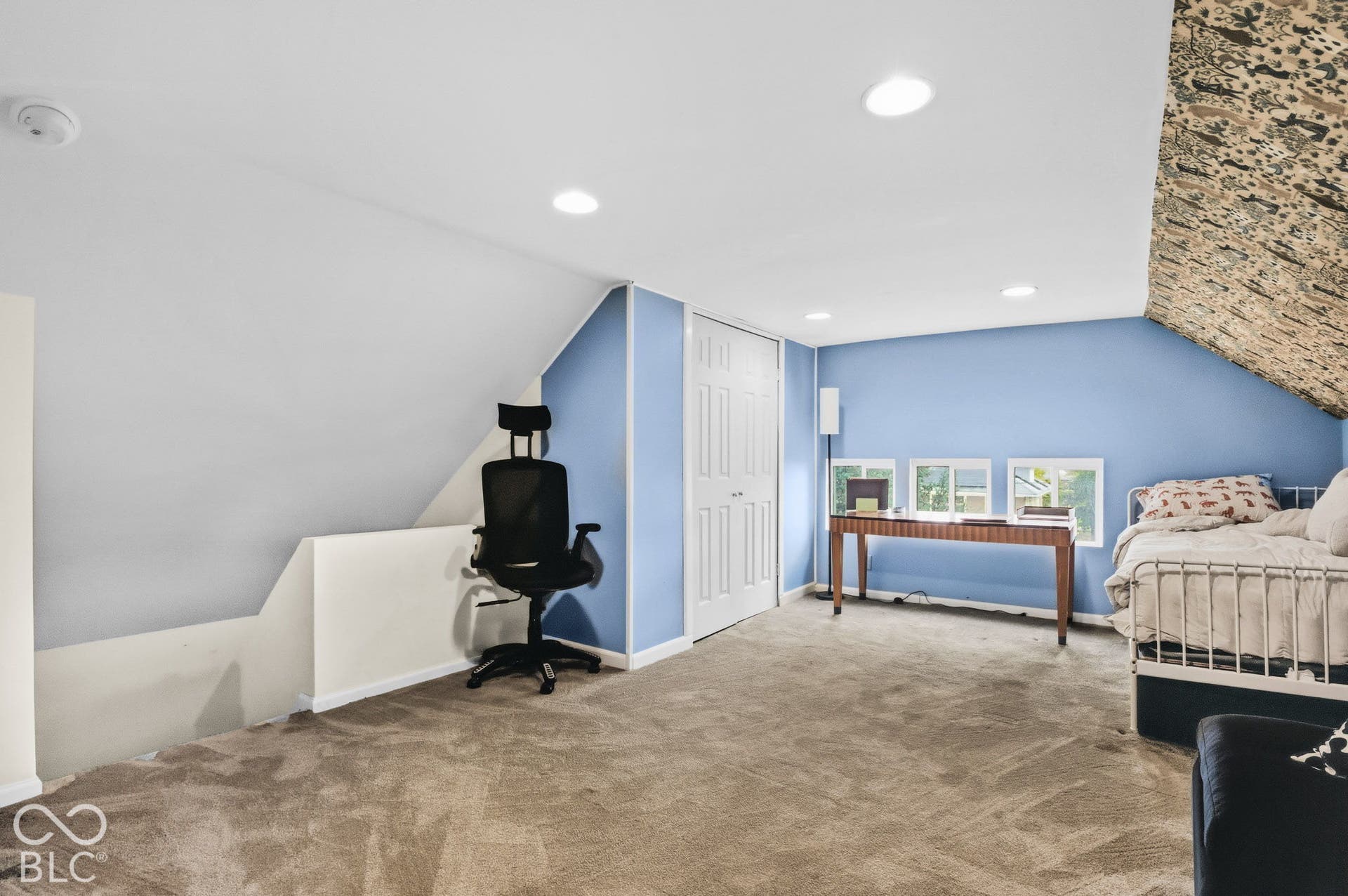 Vaulted ceiling featuring a decorative stone accent wall, recessed lighting, carpeted flooring, and a multi-panel door closet