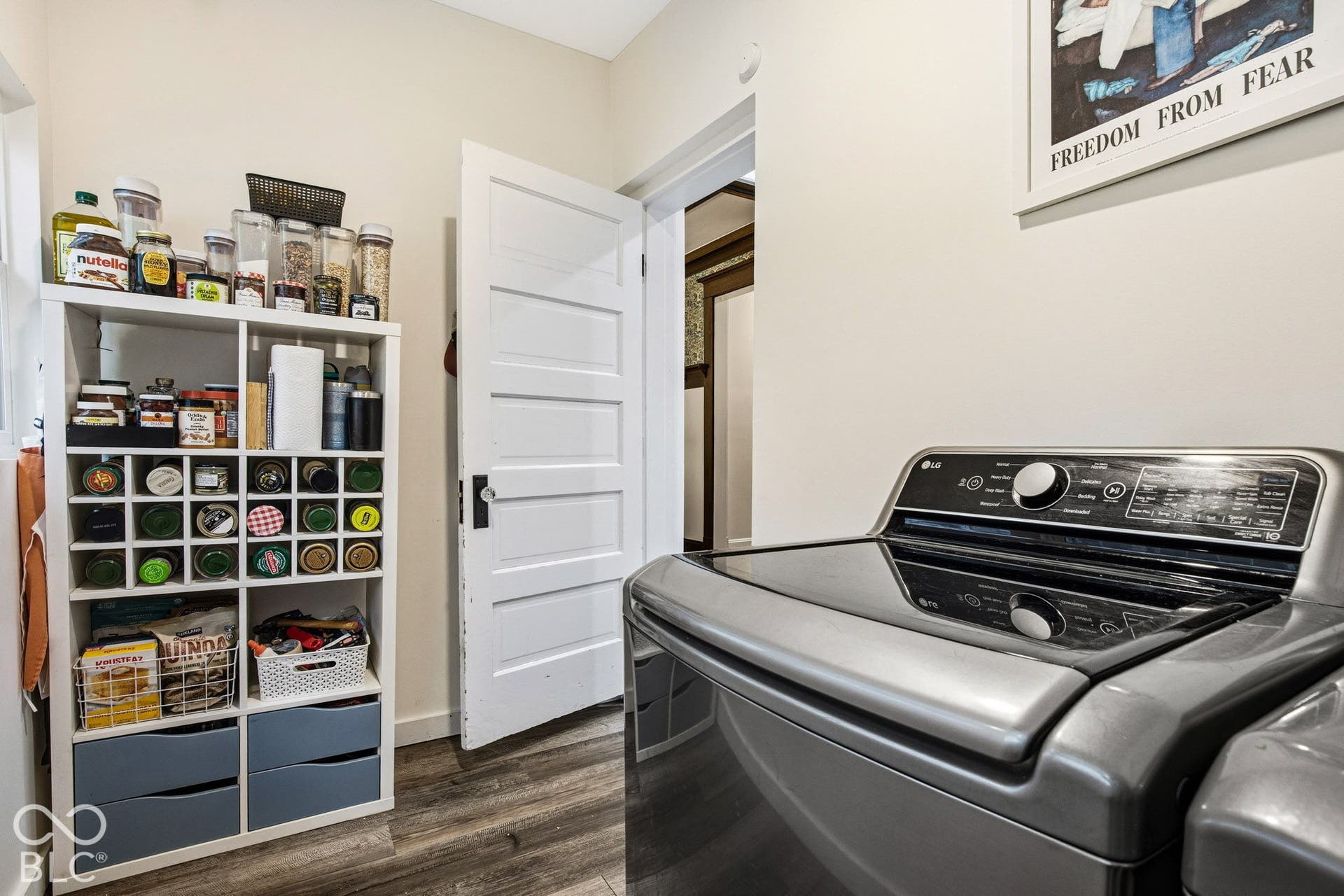 Space featuring wood-finish flooring, a five-panel interior door with period-style hardware, and neutral wall tones