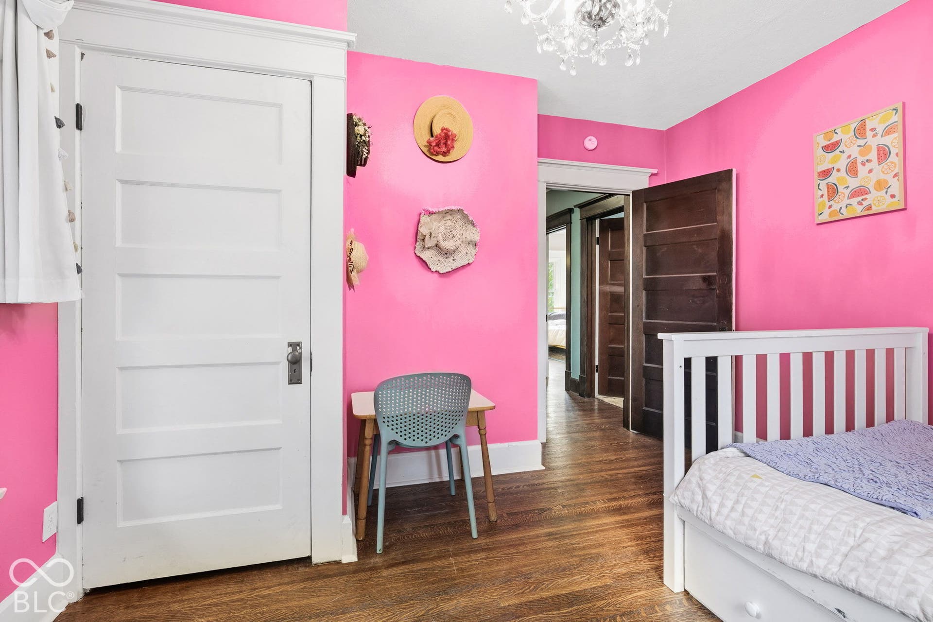 Room featuring original stained wood doors, wood-finish flooring, white wood trim, and a multi-tiered crystal chandelier