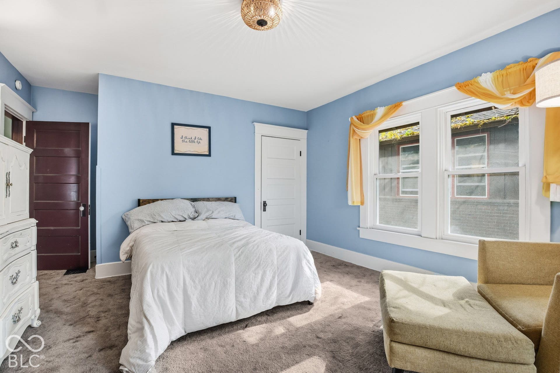 Room featuring neutral carpeting, white door and window trim, two large windows, and a flush-mount decorative ceiling fixture