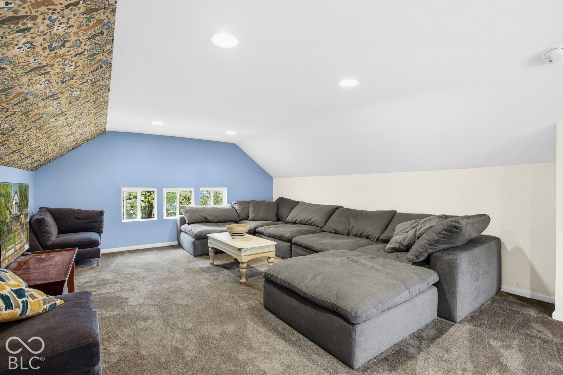 Sloped ceiling room featuring recessed lighting, patterned wall covering, and neutral carpeting
